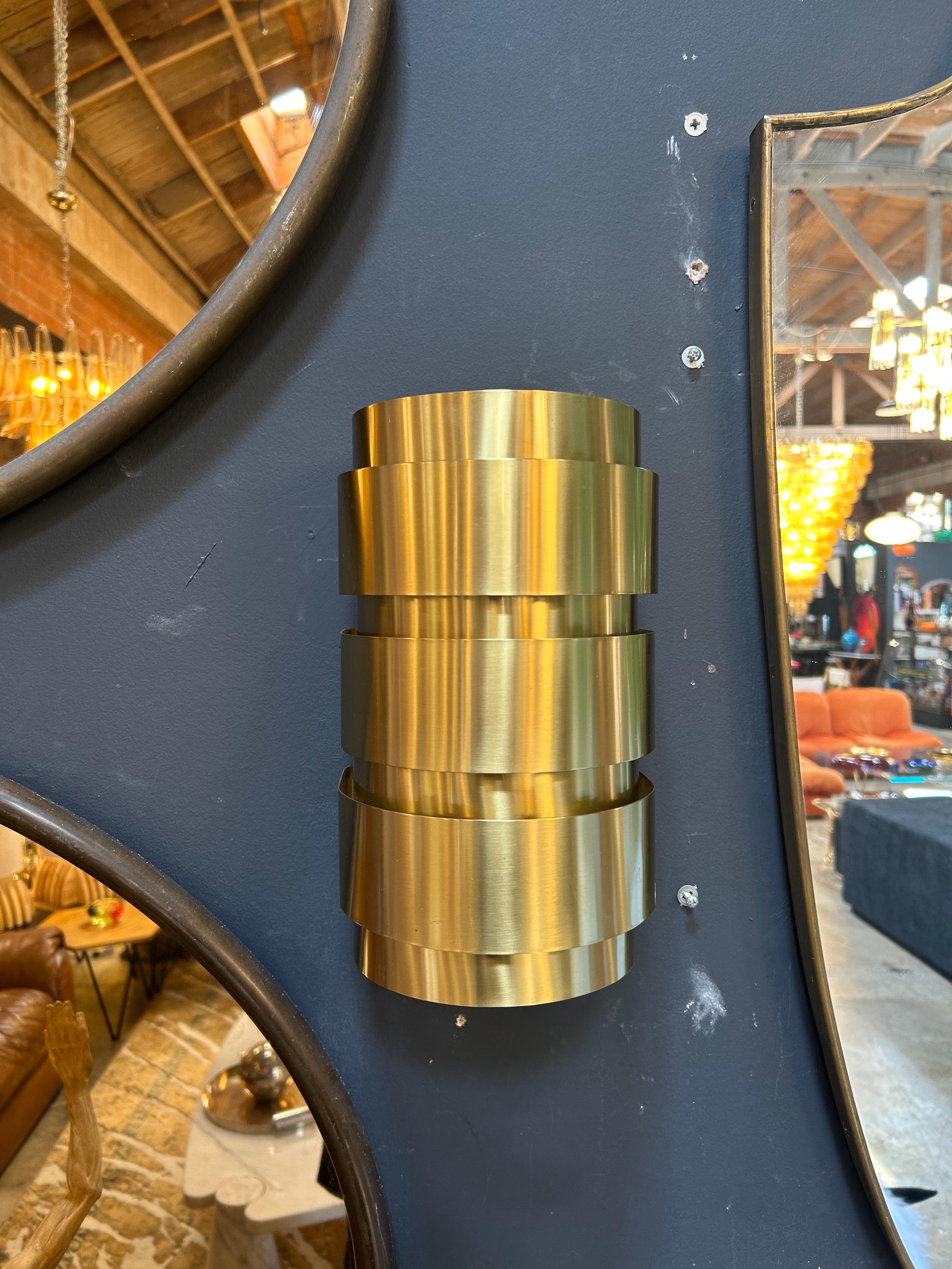 These exquisite 1960s wall sconces by Hans-Agne Jakobsson showcase his mastery of sculptural brass lighting and diffused illumination. Their tiered cylindrical design, crafted from overlapping brushed brass bands, creates a warm, ambient glow a