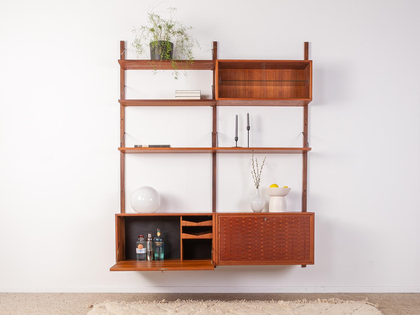Classic shelving system from the 1960s. The high-quality containers and shelves are veneered in teak. The system consists of four shelves, one container with a hinged door and internal drawers, one container with hinged door and two shelves, one