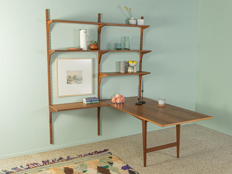 Rare Poul Cadovius shelving system with integrated desk or dining table element. The system consists of six shelves, a fold-out table and three wooden ladders in teak veneer.

Quality Features:
    accomplished design: perfect proportions and