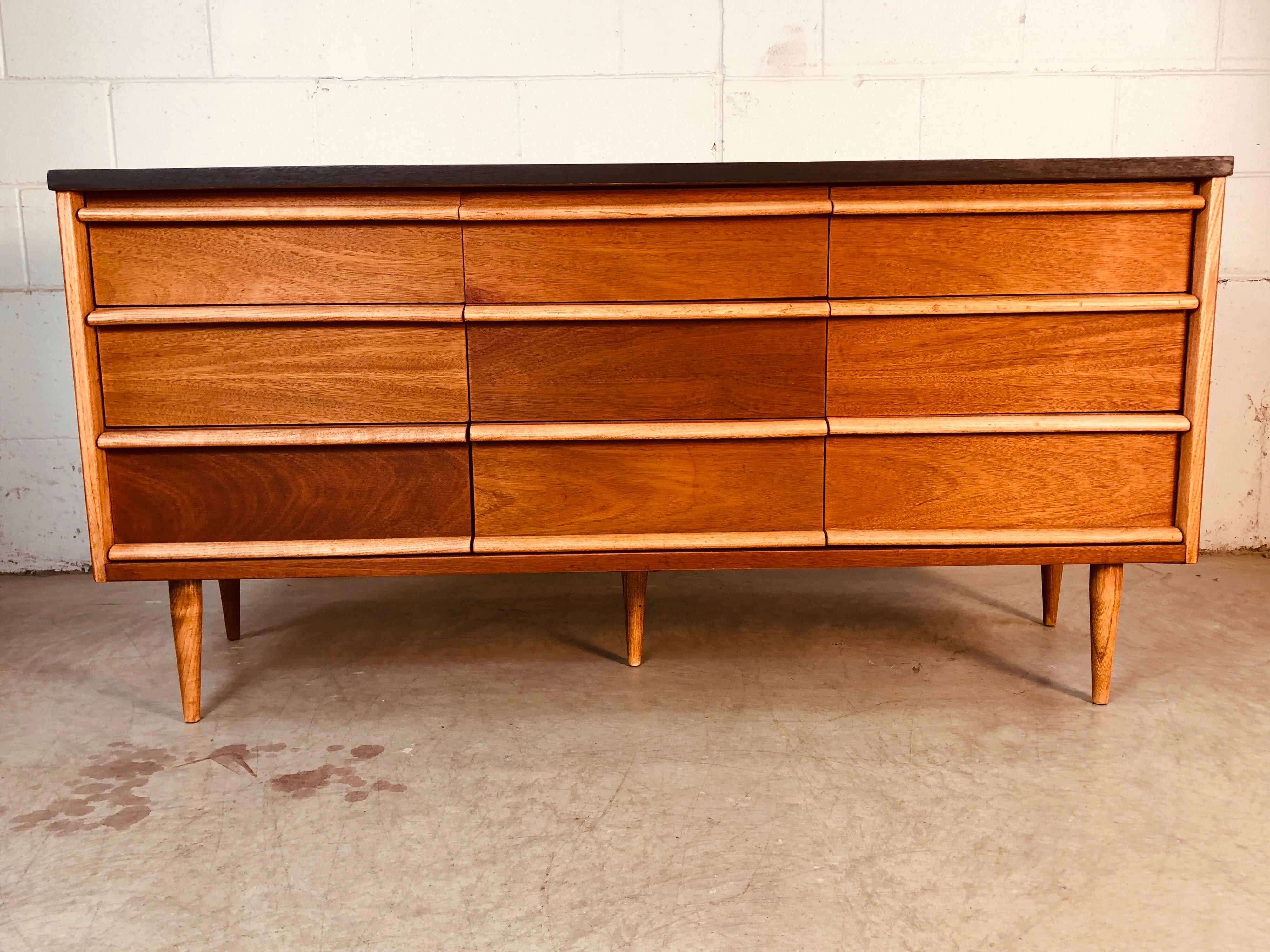 Vintage 1960s nine-drawer desser with a black painted top. The dresser has walnut wood sides and drawer fronts. The handles and feet are ashwood along with other accented spots. The dresser is fully refinished. Marked Bassett Furniture in the drawer.