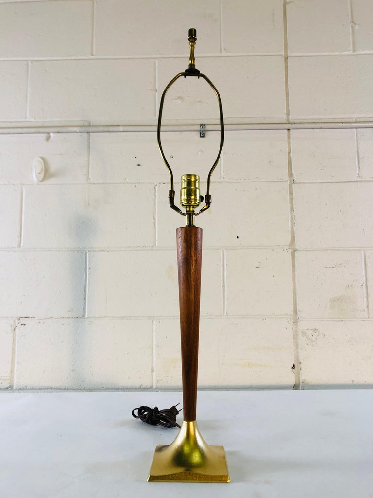 Vintage 1960s walnut wood table lamp by Laurel Lamp Co. The lamp is gold metal with walnut wood and is in refinished condition. The lamp works and the shade is not included. Socket, 18.5” height. Harp, 4.5” diameter x 10” height.