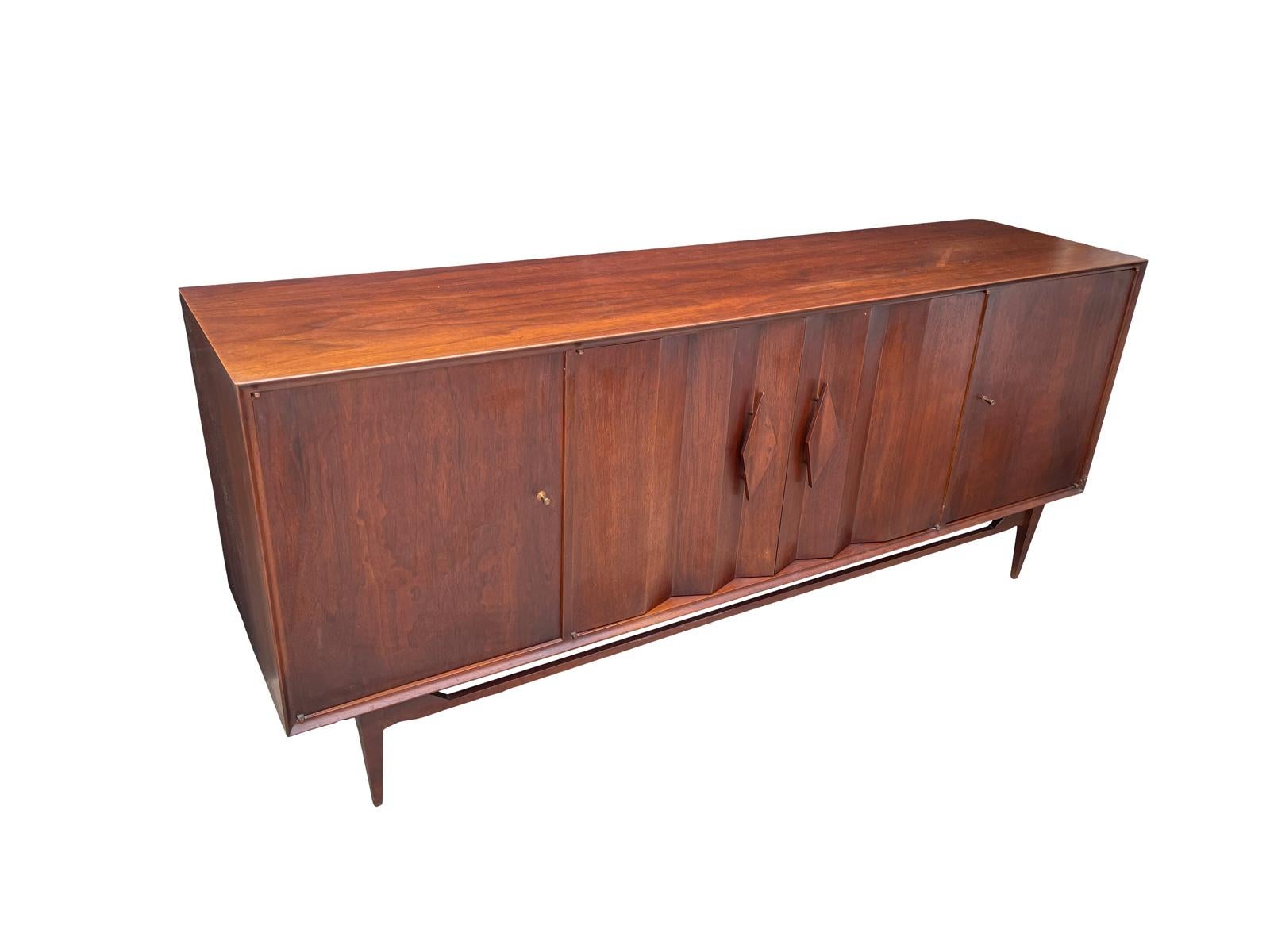 Handsome walnut credenza by specialty woodcraft circa 1960s featuring a unique sculpted front and base very rare.Also listed is the matching dining table and chairs if you want the complete set