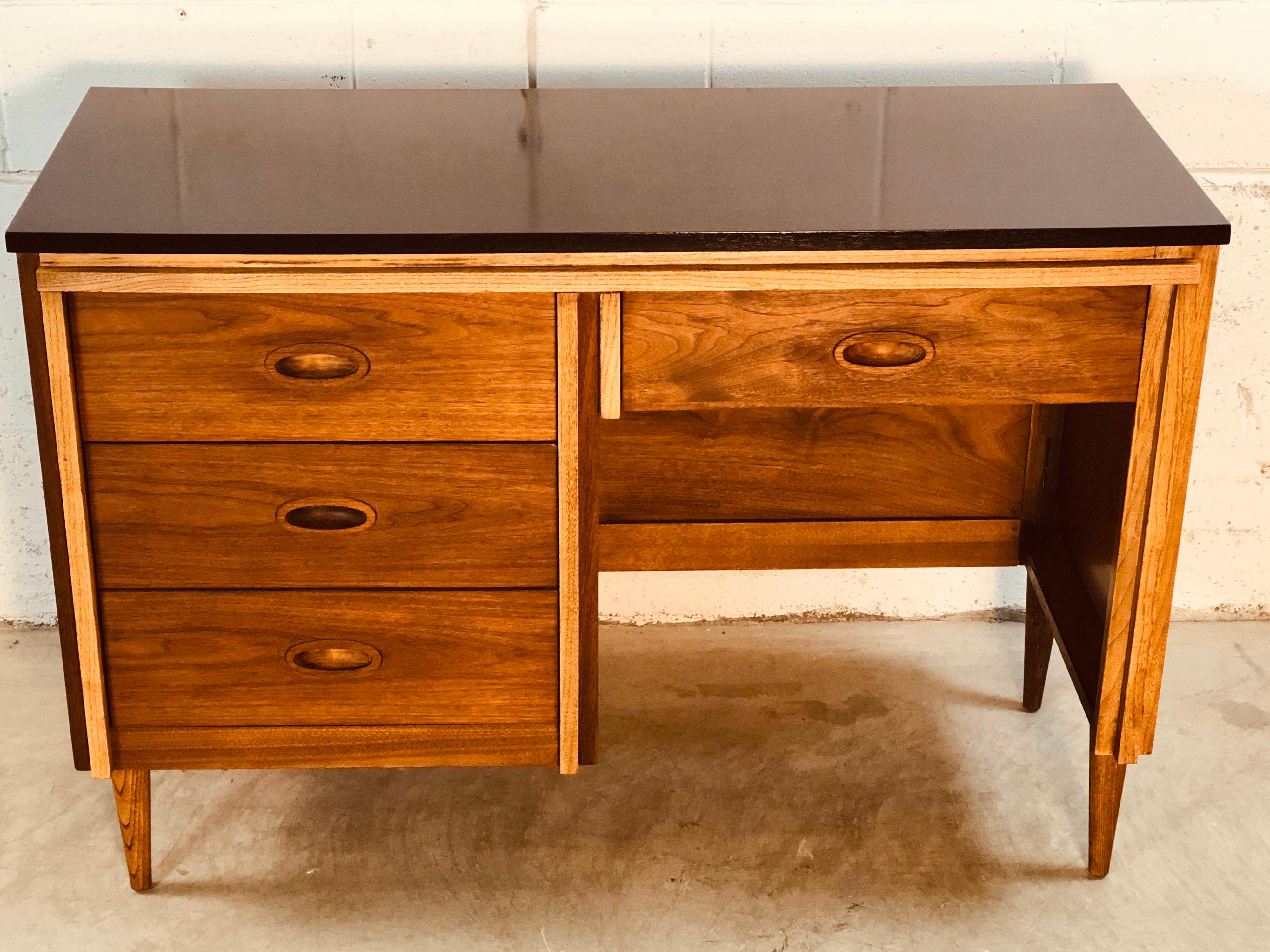 Vintage 1960s walnut and ashwood single stand desk by Dixie Furniture Co. The four-drawer desk has been fully restored and the desk top has been painted black. The desk has ash wood accents on the front and the legs. Knee hole is 20” L x 23” H.