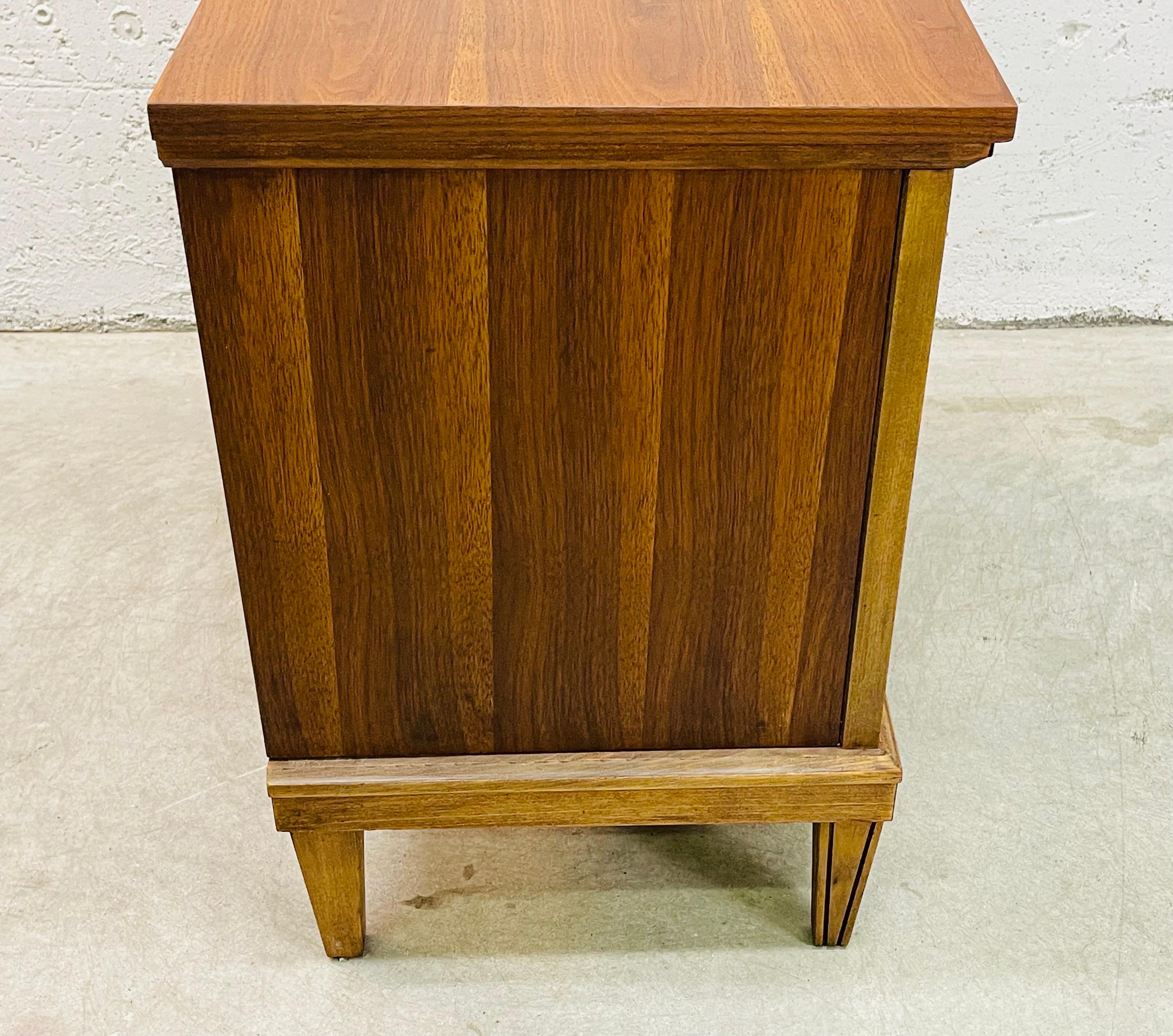 Vintage 1960s walnut and maple wood two drawer bedroom nightstand. The nightstand has a beautiful walnut wood grain and the drawers are accented with maple wood. Newly refinished condition. Marked with a label inside.