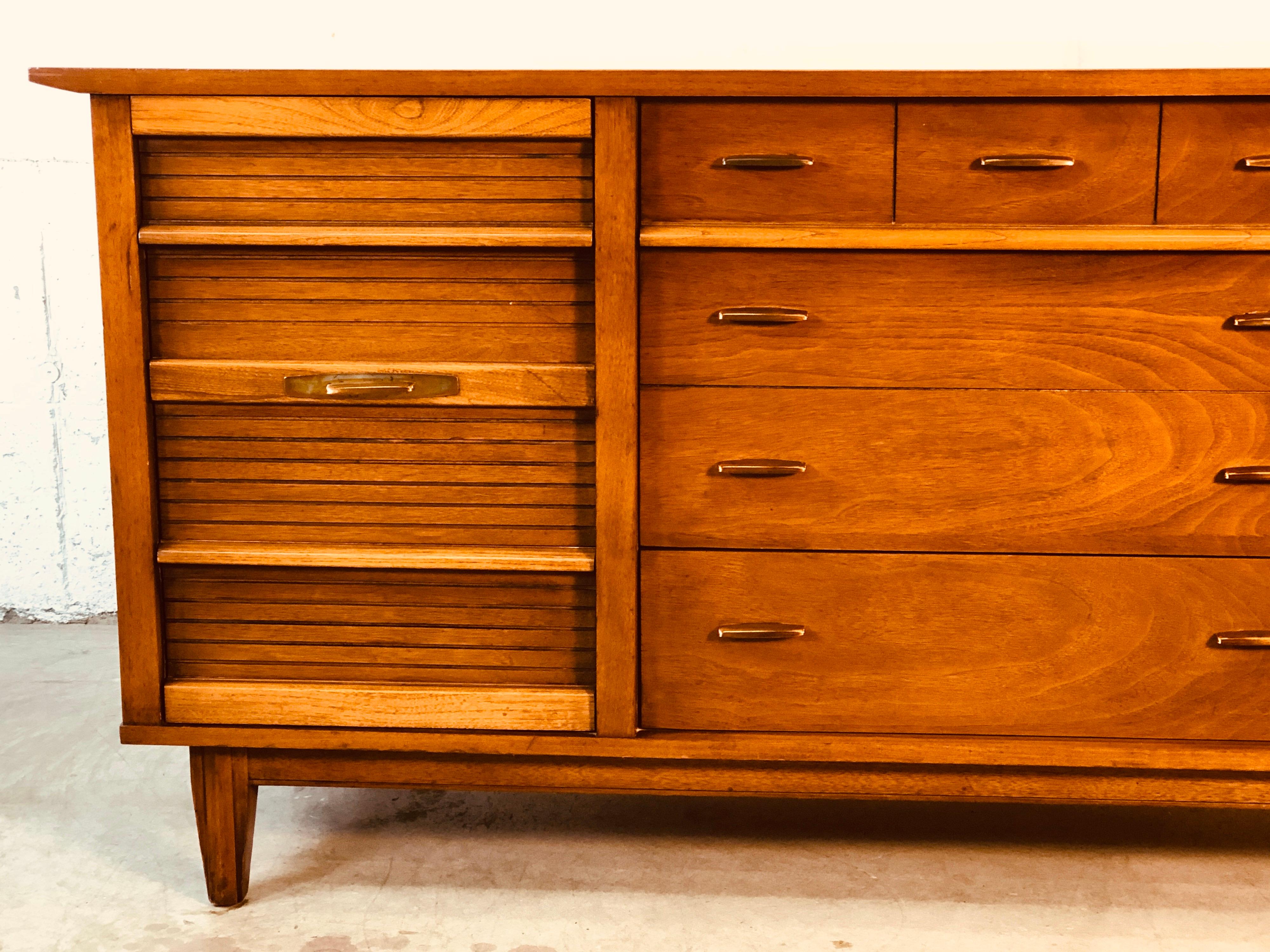 Vintage 1960s walnut wood nine drawer low dresser by Dixie Furniture Co. The dresser has brass pulls and deep drawers for storage. Marked.
