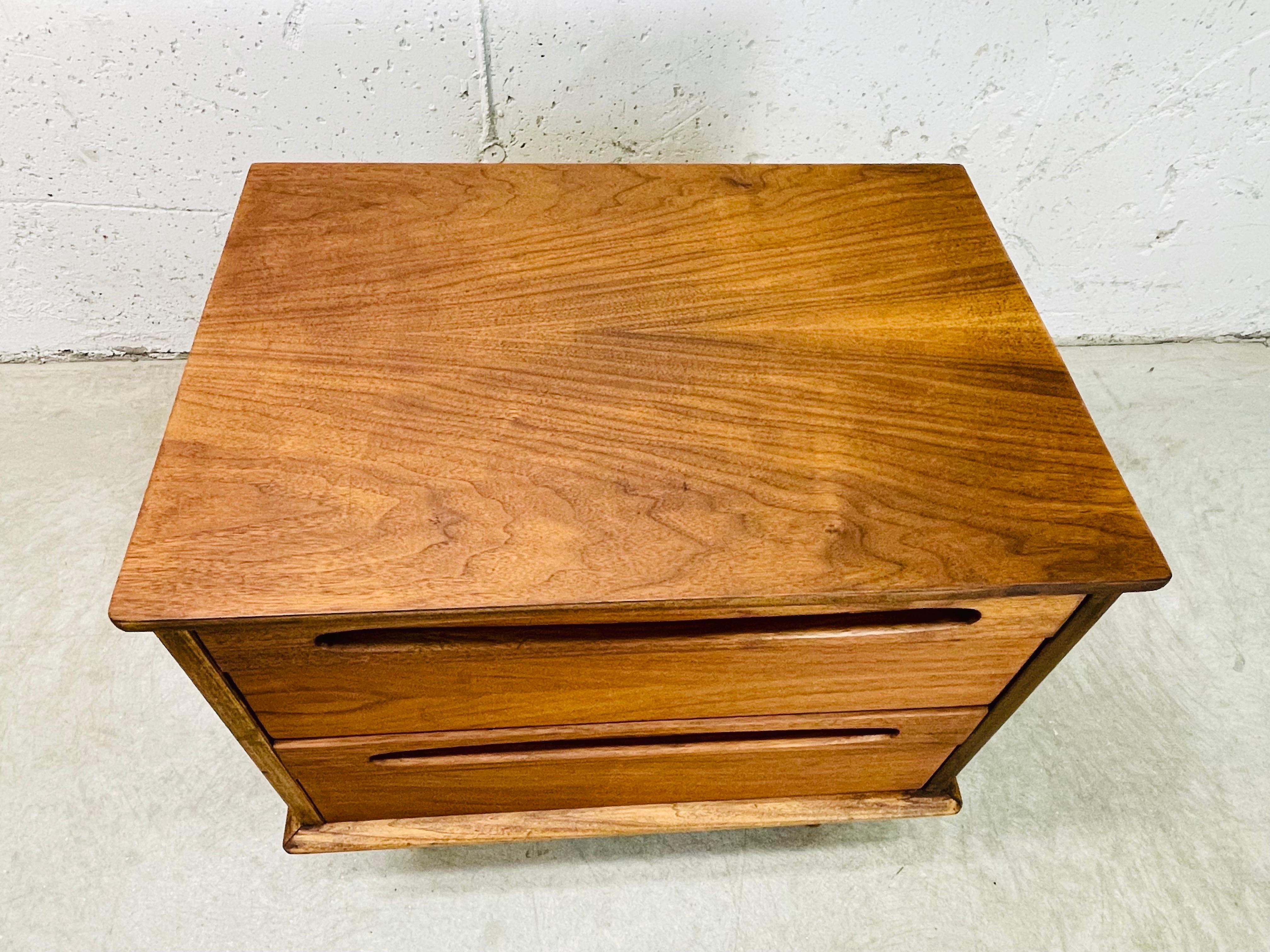 Vintage 1960s solid walnut nightstand by American of Martinsville. The nightstand has two drawers for storage and round turned legs. The drawers are 4.5”H. Marked in the drawer.