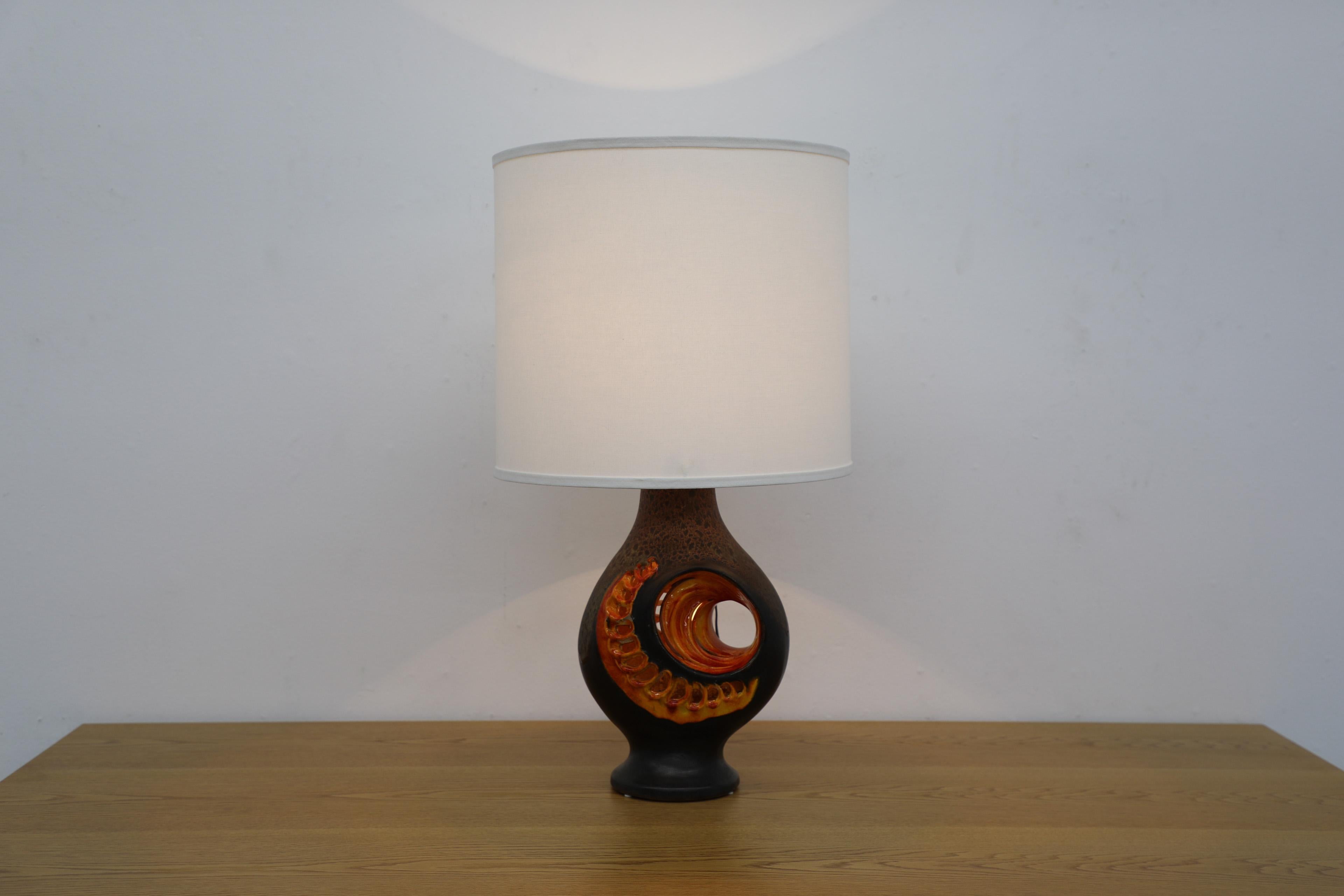 Great West German fat lava glazed ceramic table lamp by Walter Gerhards for Herda with interesting swirl design and a new linen shade. Features standard light bulb and also an internal bulb that illuminates the swirl. The body measures 11 x 8 x 20.