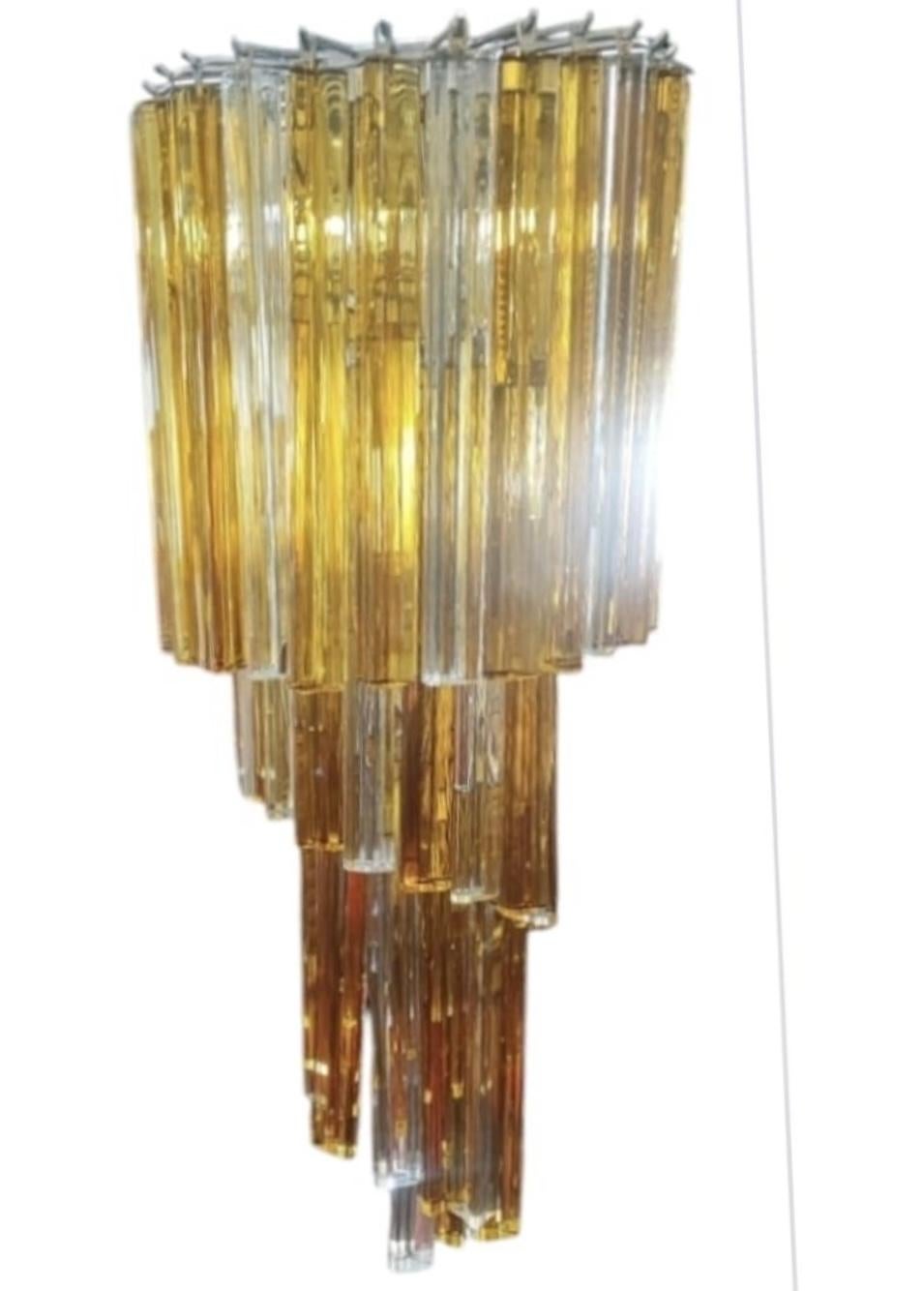 Esta araña en espiral trilobi de cristal de Murano amarillo y blanco es un impresionante ejemplo de artesanía italiana, con elementos de cristal soplado a mano con un característico diseño trilobulado (trilobi) dispuestos en cascada. Estas lámparas