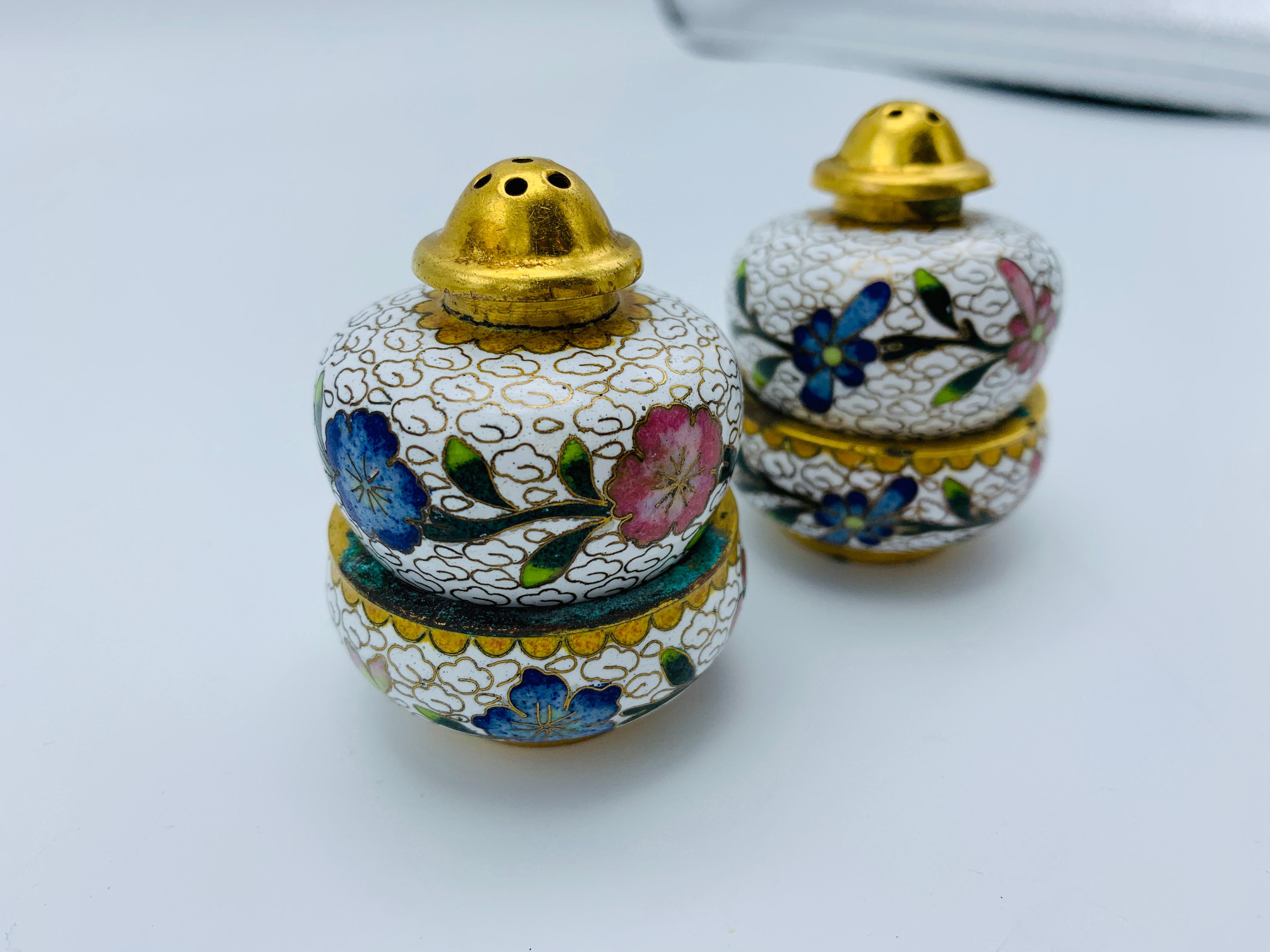 Listed is a gorgeous, set of 2, 1960s Cloisonné salt and pepper shakers. The shakers have removable brass caps, for easy refilling. The shakers rest upon the cellars below. The shaker measures: 2.25