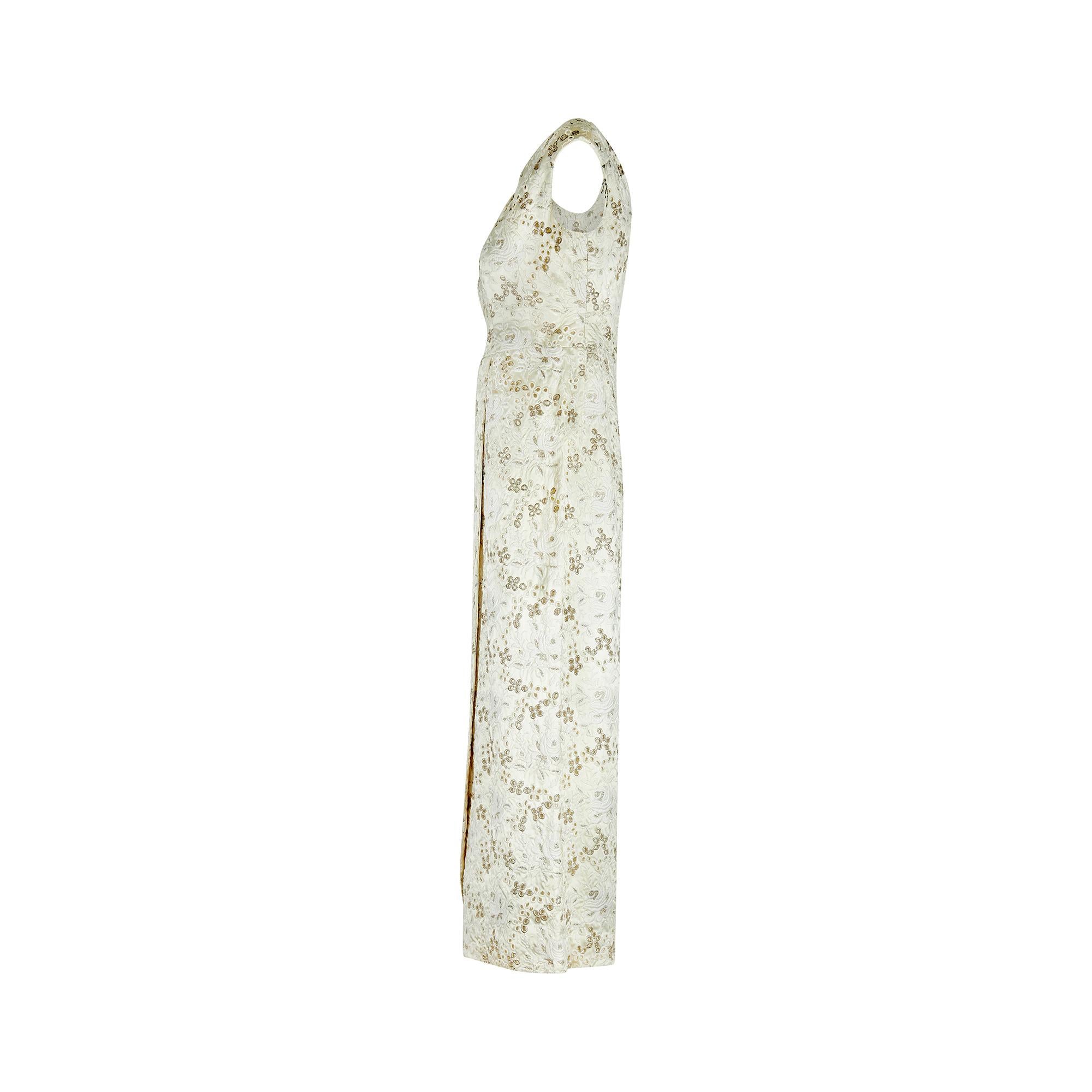 This 1960s column dress is deceptively simple and the epitome of elegance for formal or bridal wear.  It is crafted from white brocade silk with a subtle sheen and detailed from head-to-toe with intricate embroidery of roses.  The floral composition