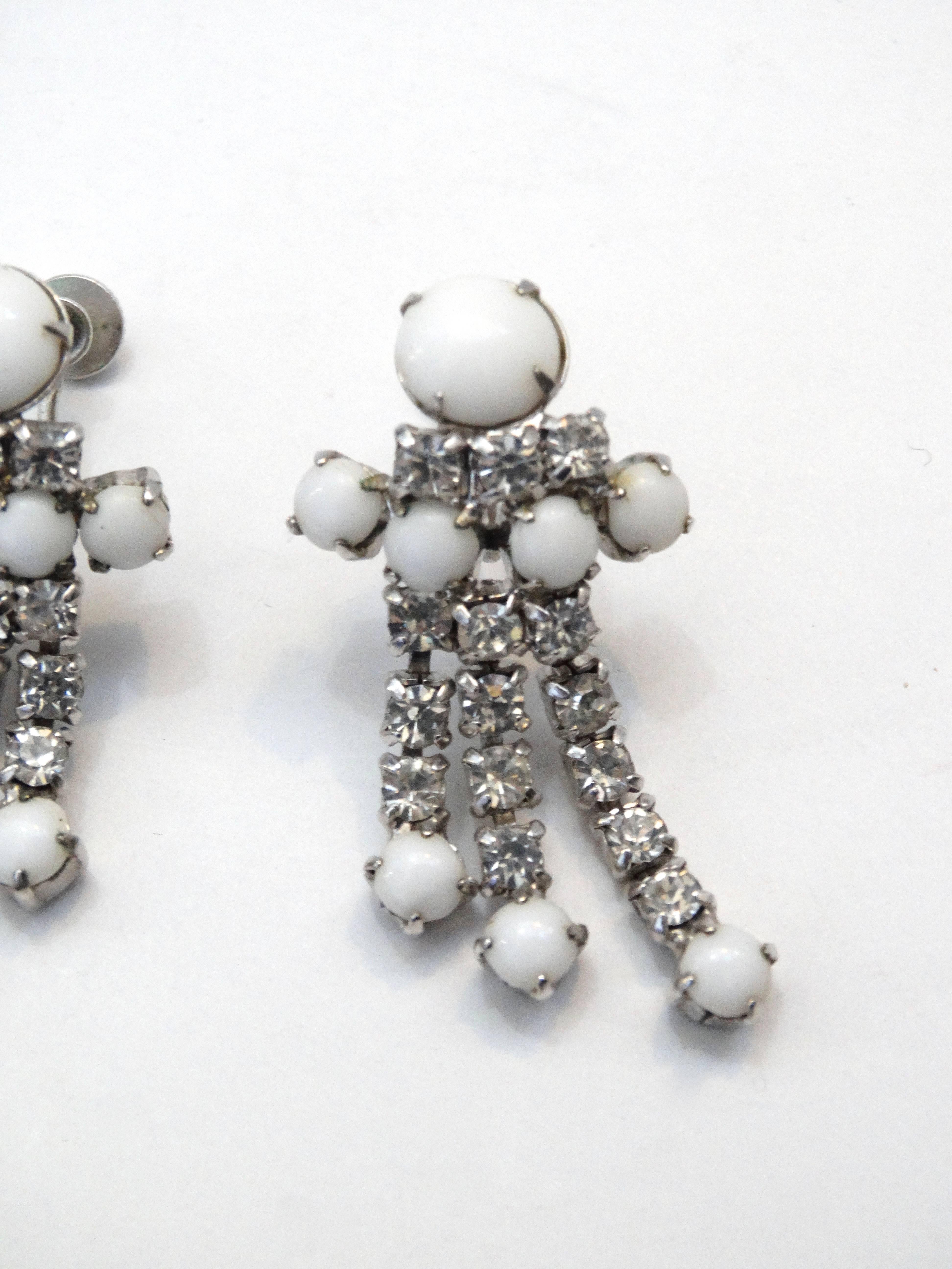 Channel the style and class of the 1960s with our adorable rhinestone dangle earrings! Milky white rhinestone gems contrasted with crystalline rhinestones, all set in silver toned metal. Cluster style charm with three strands of rhinestones