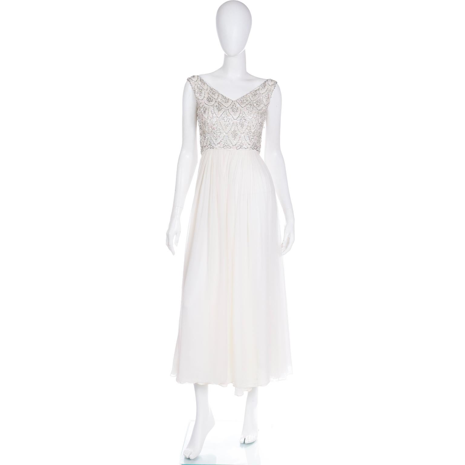 This princess worthy white silk chiffon evening dress is truly magical with its beaded bodice and flowing full skirt. This 1960's dress has a v neckline and shimmering silver beads and iridescent sequins. There is a center back zipper for closure