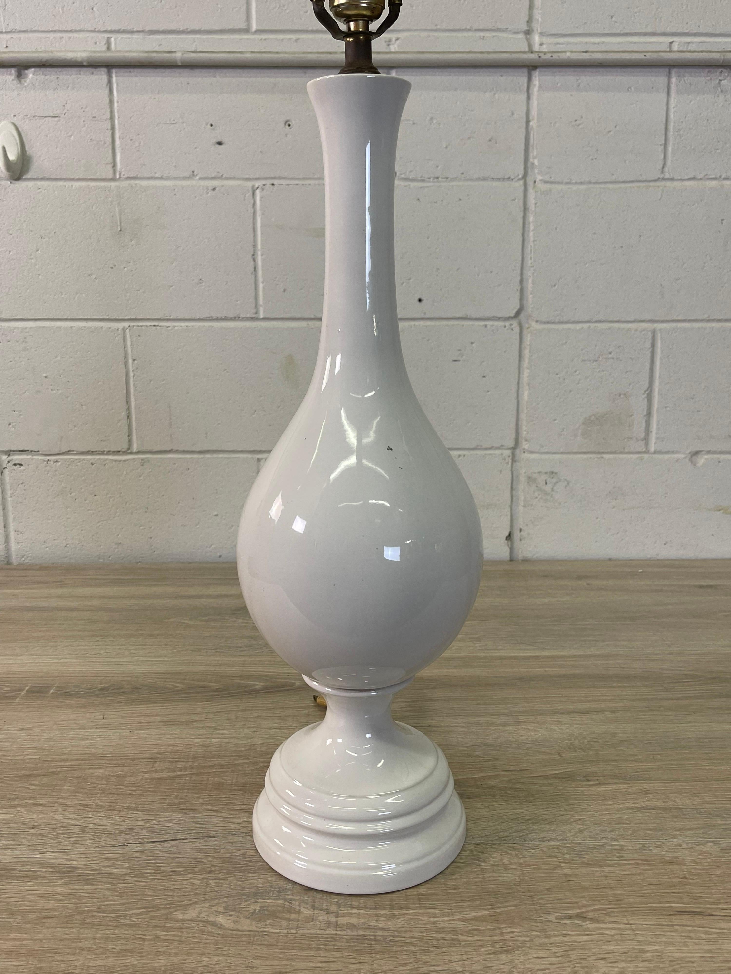 Vintage 1960s tall white ceramic table lamp. Wired for the US and in working condition. Lamp uses a standard 100 watt bulb. Harp, 4.5” Diameter x 10” Height. Socket, 25”H. No marks.