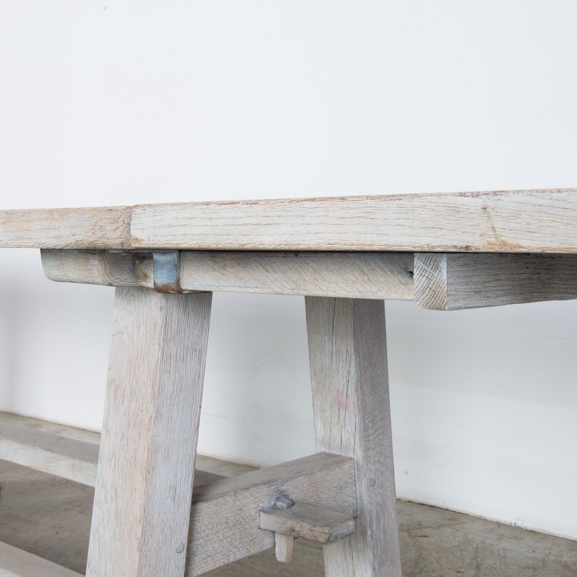 This bleached oak dining table was made in Belgium, circa 1960. Removable extensions on each side allow you to easily convert this into a large table for a gathering. The tabletop consists of four hefty planks that rest on a solidly constructed