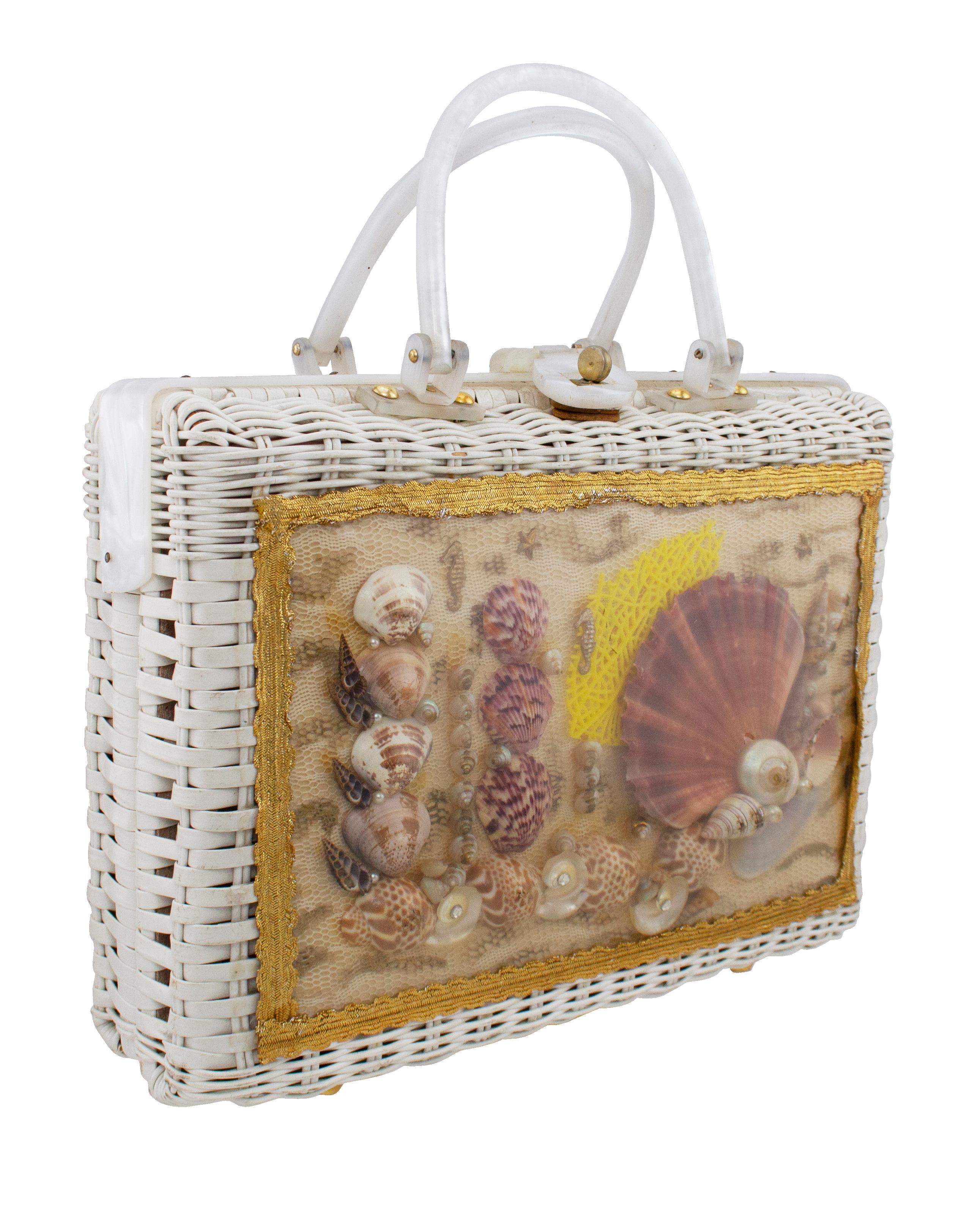 This 1960s top handle bag is so much fun! Frame style bag with white wicker body and a pearlized white frame and top handles with brass screws. The front features a collage of real 3D seashells on a piece of cream and tan macrame, that gives the