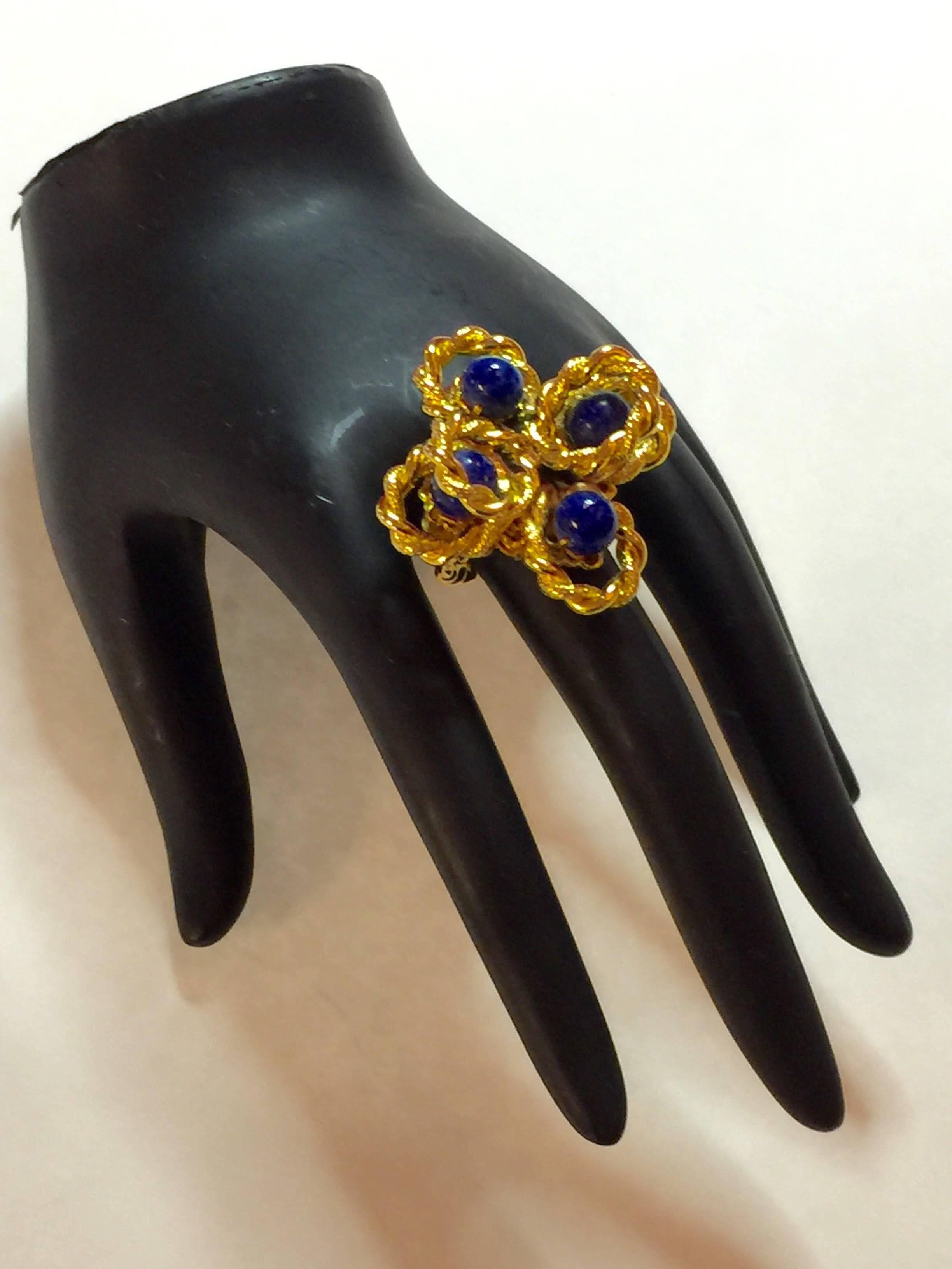 Offered here is this 1960's William DeLillo Faux Lapis Goldtone Fits EVERYONE Cocktail Ring. In classic late 60s braided/molten gold style, this ring has an open back shank and can be self-custom bent to fit most wearers. The double braided and