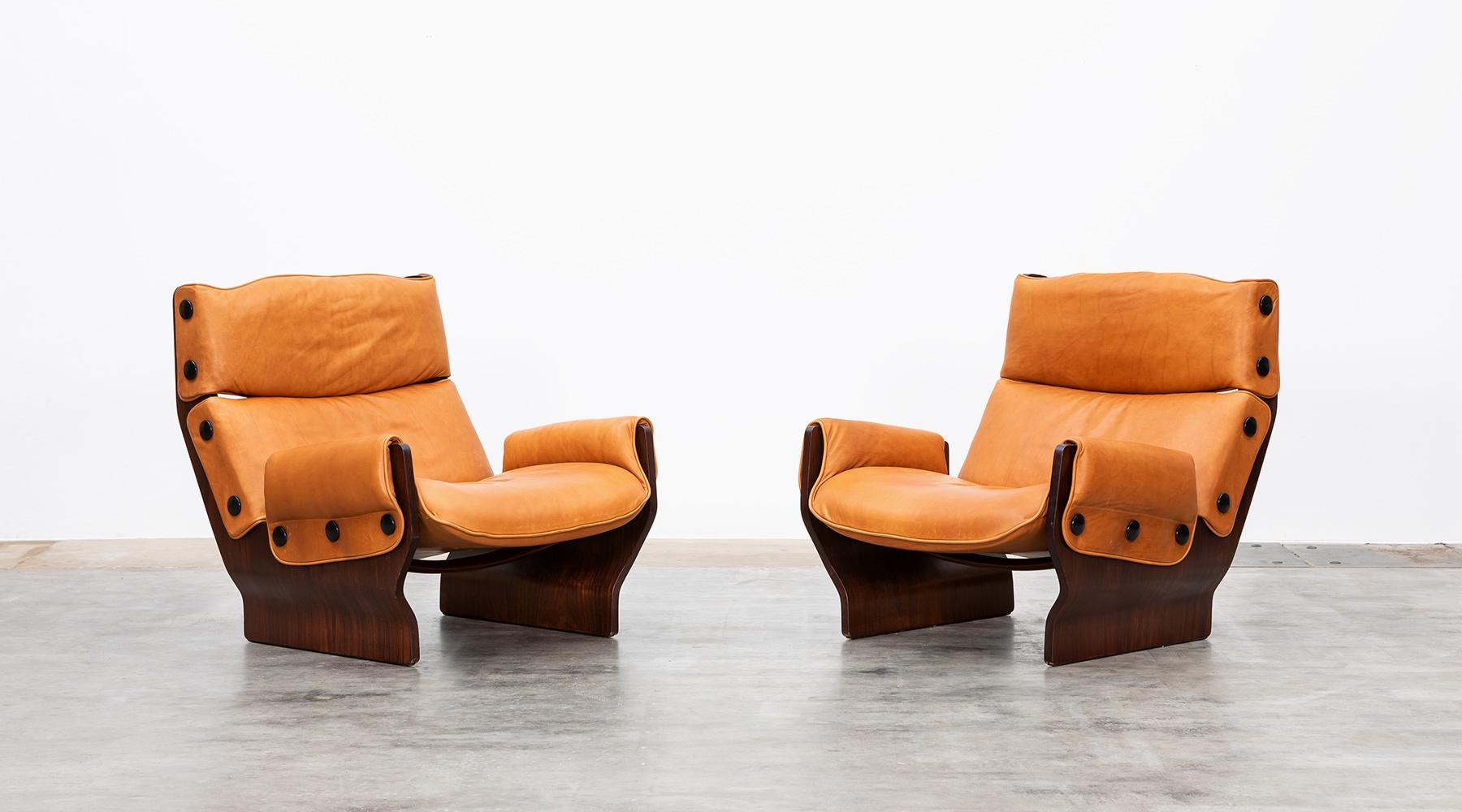 Two majestic, rustic lounge chairs designed by famous Osvaldo Borsani. The seats are newly upholstered in high-quality leather and comes on a wooden base. On the sides are decorative button borders, which are also made of wood. A wonderful