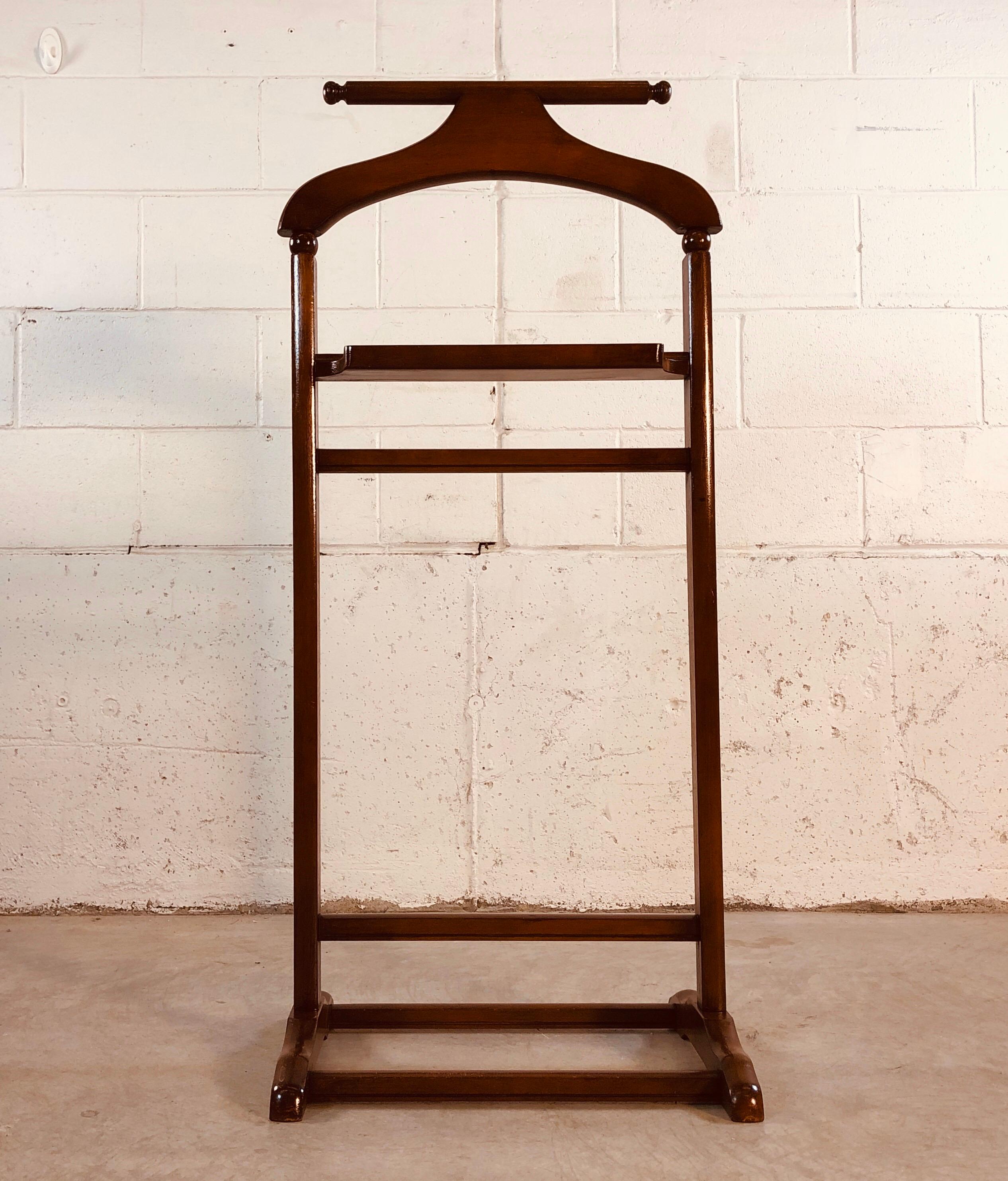 Valet de chambre en bois foncé des années 1960. Le valet a une petite étagère au milieu. Excellent état restauré. Aucune marque.