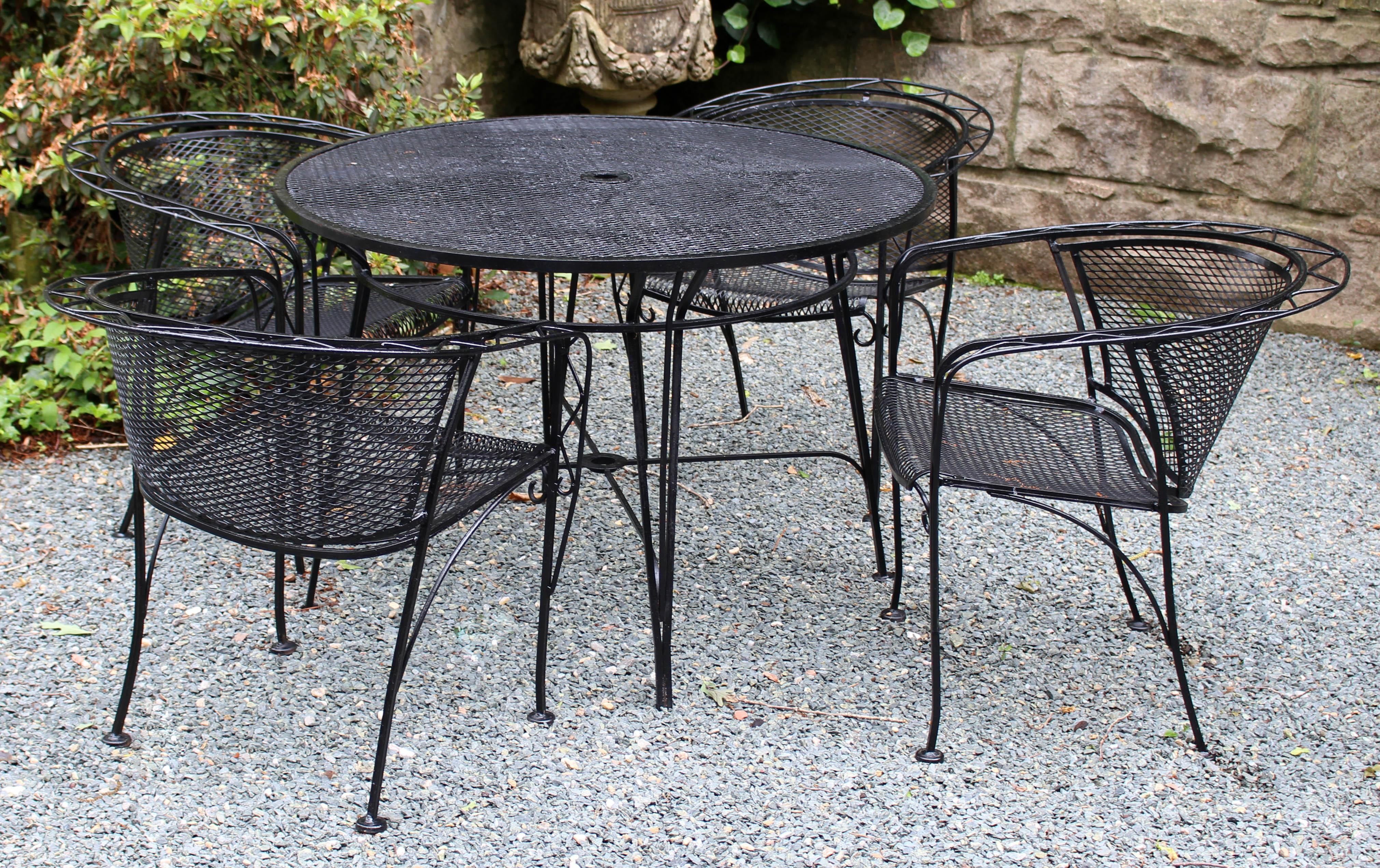 Wrought iron table and four tub chairs, c.1960s, from Style Craft of Chapel Hill. Most certainly Woodard. Unusual saw tooth arm motif. Very stable umbrella stand table base form. Repainted over the years. Table: 42
