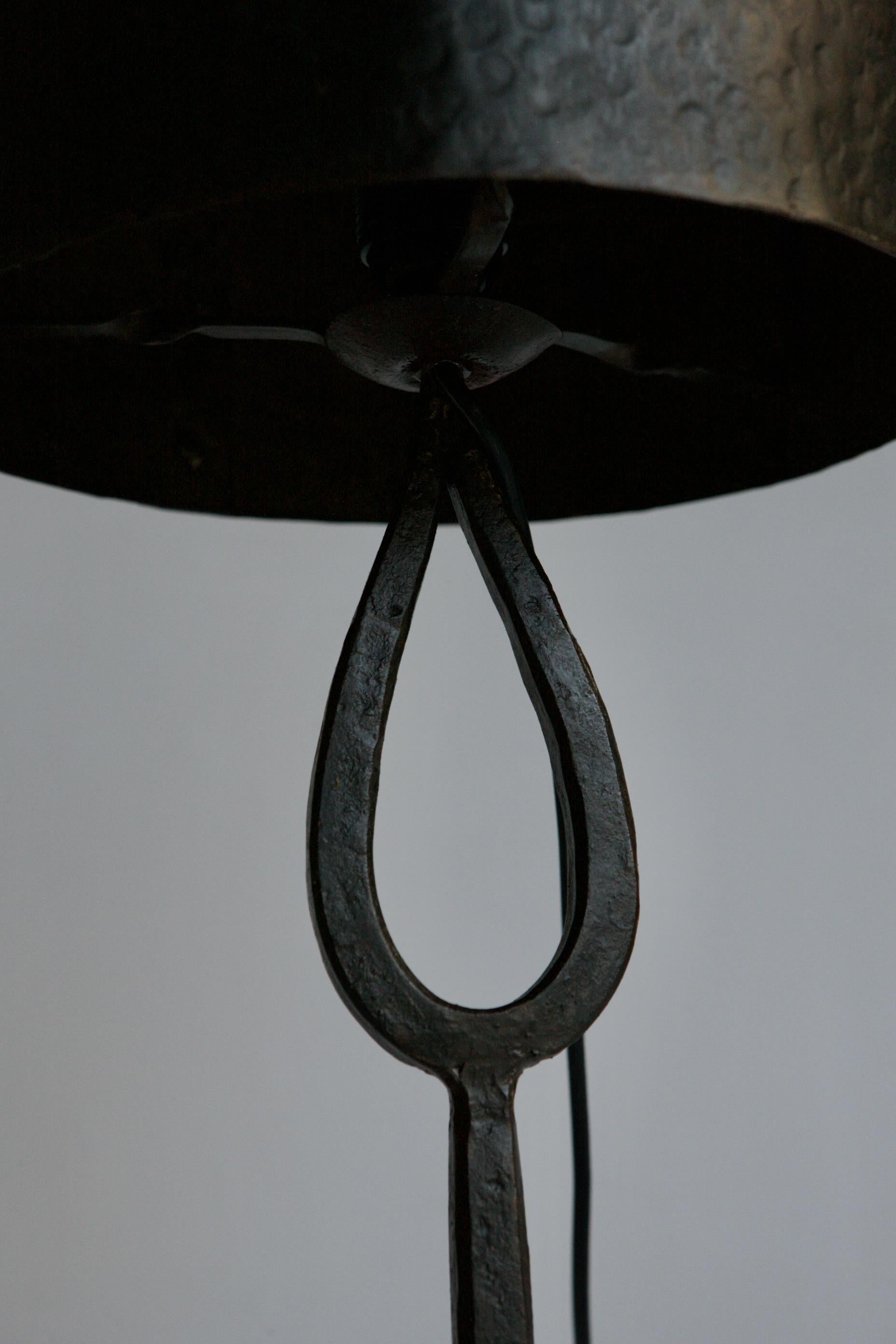 A artisan wrought iron table lamp. Made in 1960's France by a metalworker. The asymmetric shade has a hammered textured and the over all feel is reminiscent of a Calder sculpture.