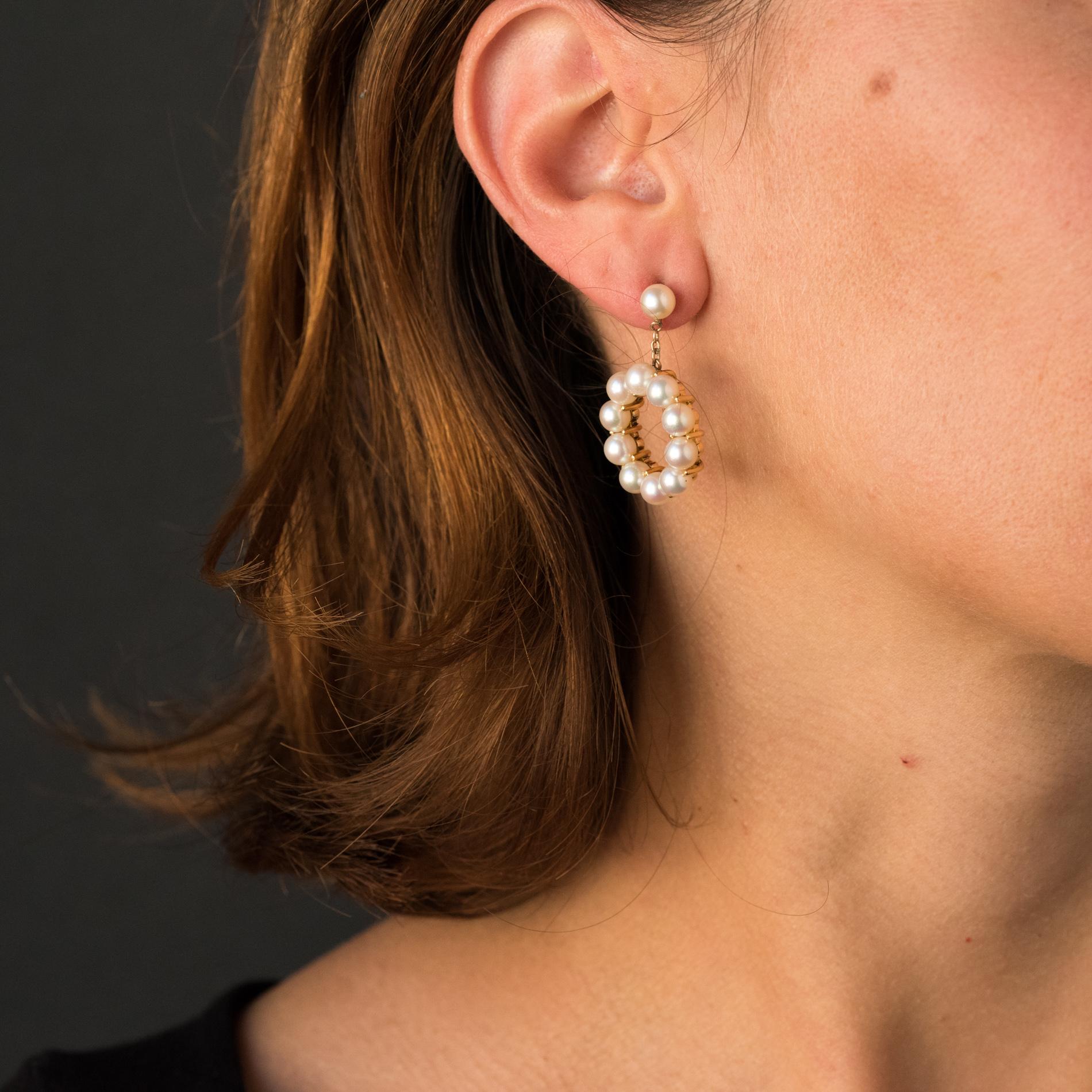 For pierced ears.
Pair of earrings in 9 carats yellow gold.
Each earring is composed of a cultured pearl, which holds by a chain, a circle adorned with cultured pearls set on all its turn. The pearls of these retro earrings have a pearly white