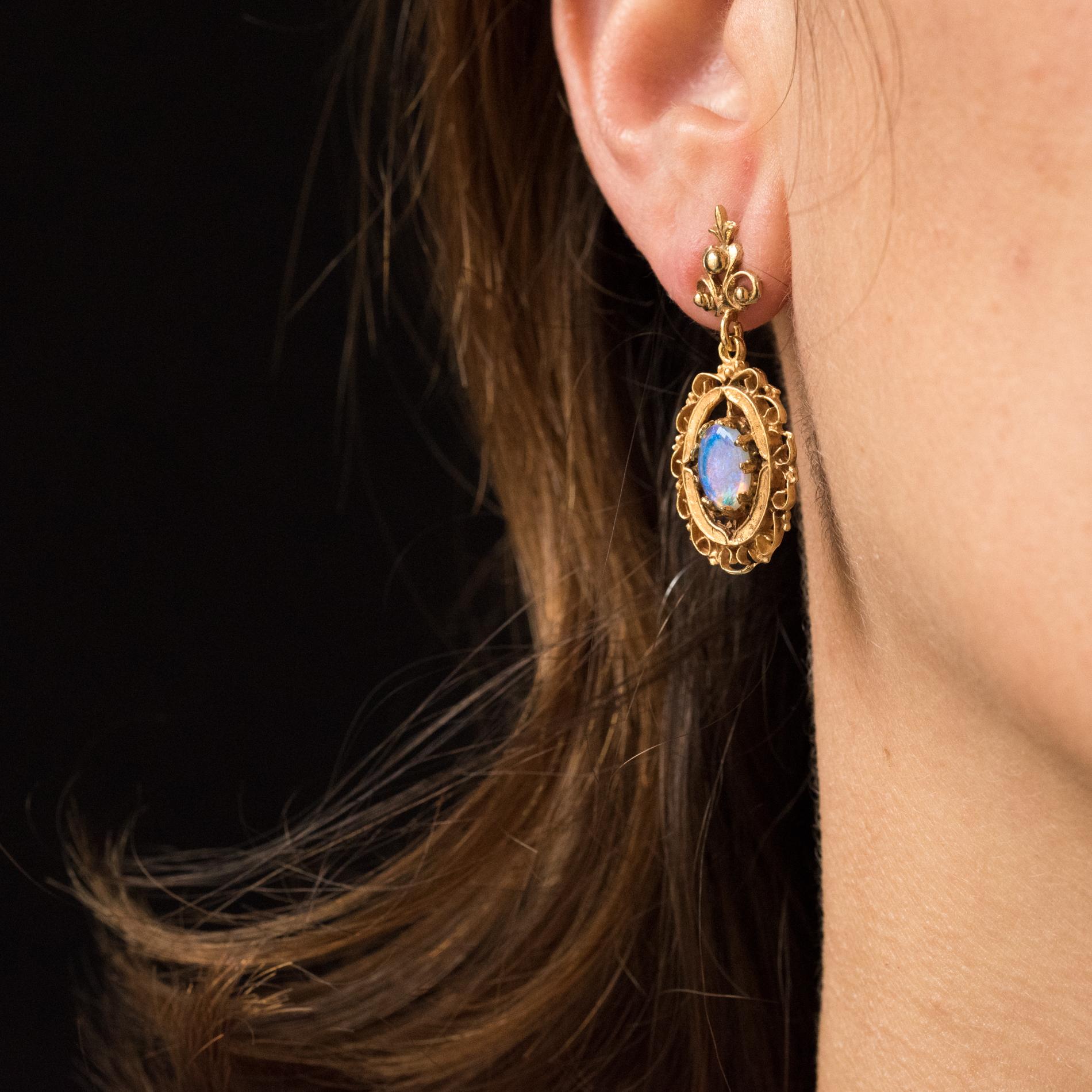 Earrings in 14 karats yellow gold.
Lovely dangle earrings, each consists of a trilobed pattern surmounted by a small lily flower. It retains an oval shaped pattern set with claws in the center of a cabochon opal. The clasp is a butterfly.
Length: