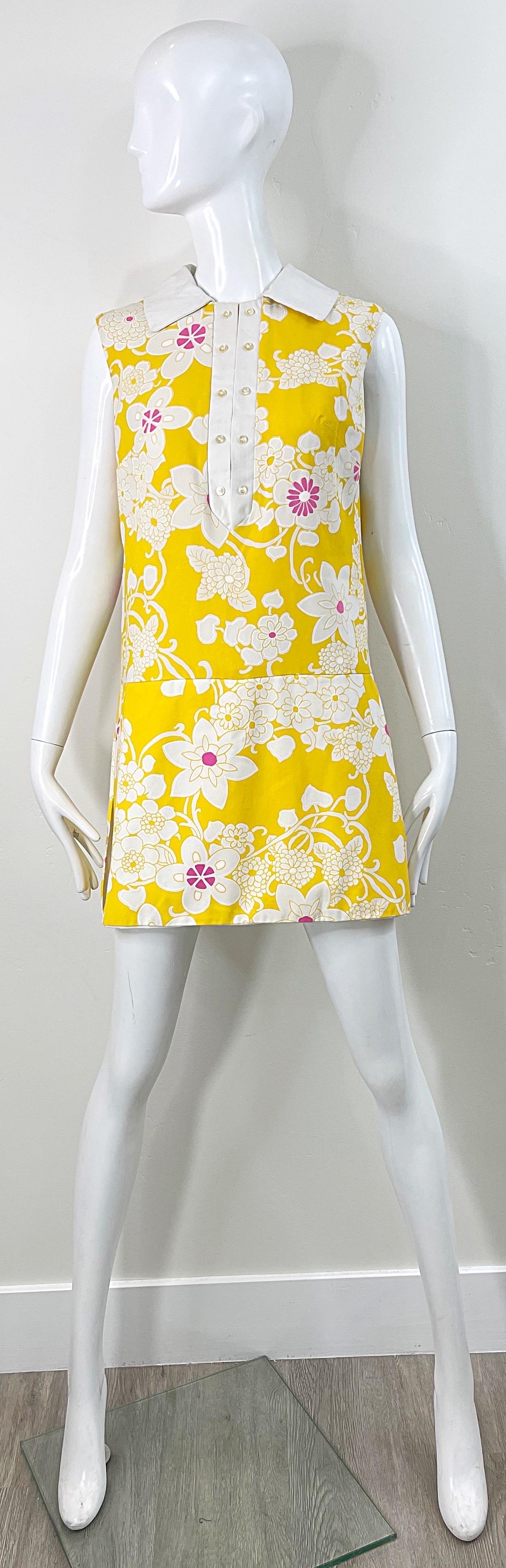 Schicker 1960er Jahre Strampler in Gelb, Rosa und Weiß ! Der Hintergrund ist leuchtend gelb und mit rosa und weißen Blumen bedruckt. Sieht aus wie ein Kleid, ist aber eigentlich ein Strampler mit einem Rock darüber. Scheinbare Knöpfe auf der