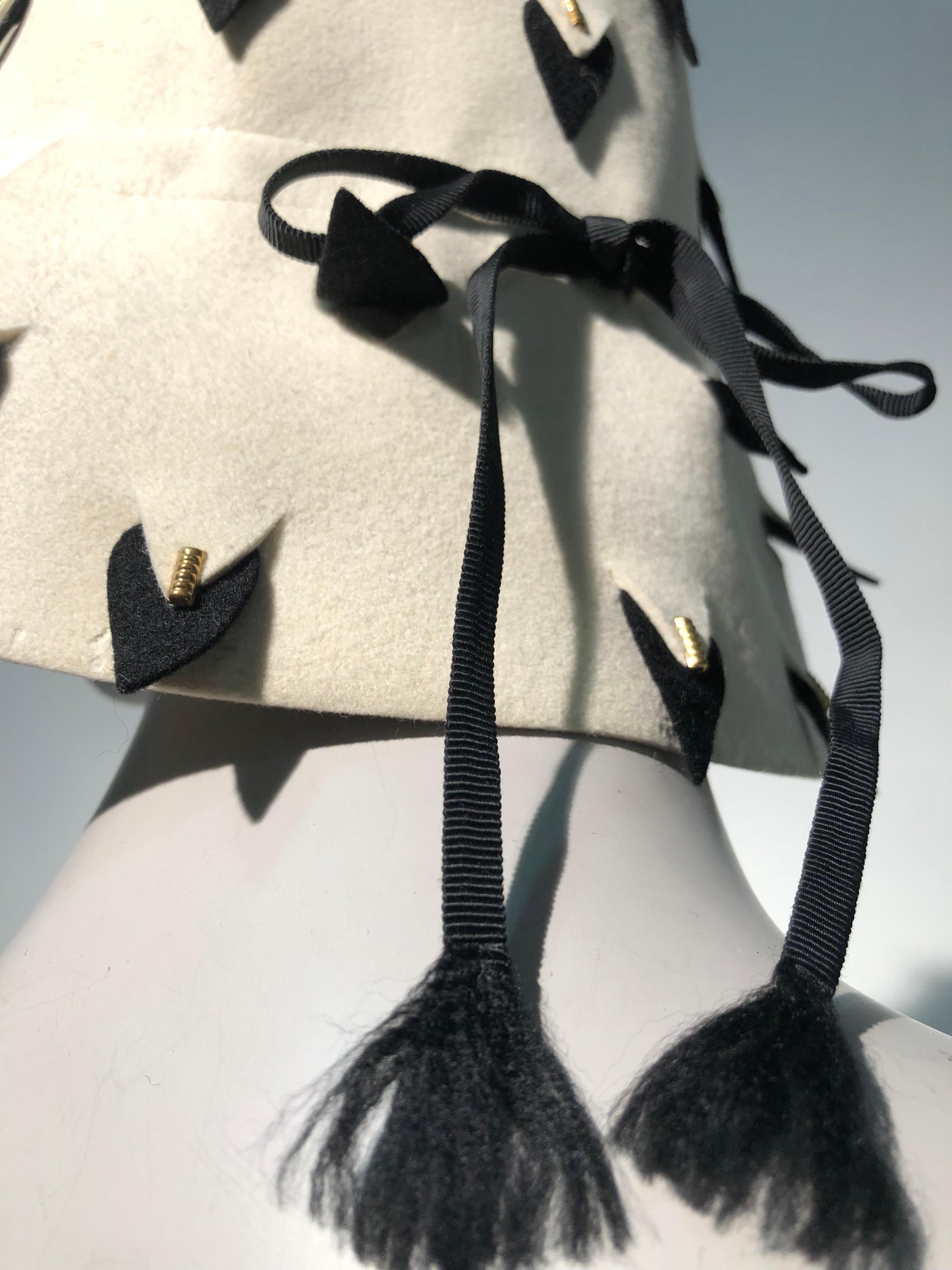 A smart  1960s Yves Saint Laurent eggshell wool felt bucket hat with graphic black and white abstract vented surface cuts throughout that resemble ermine tails. A narrow black hatband is tied in a bow. Contrasting signature YSL turquoise blue
