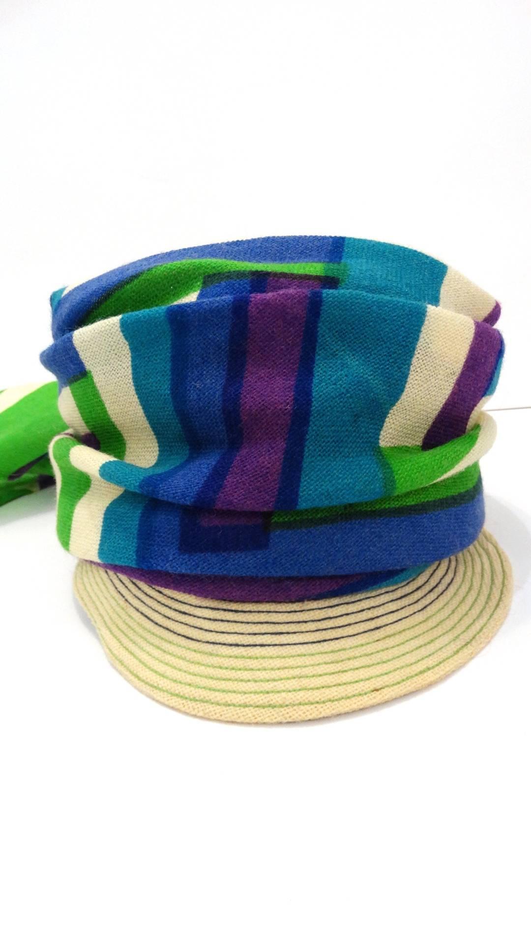 Your perfect summer hat has arrived- with our amazing 1960s Yves Saint Laurent headscarf hat! Woven straw brim with purple and green stitching. Wrapped with blue, violet and green striped scarf, knotted at the back. Lined with grey fabric and