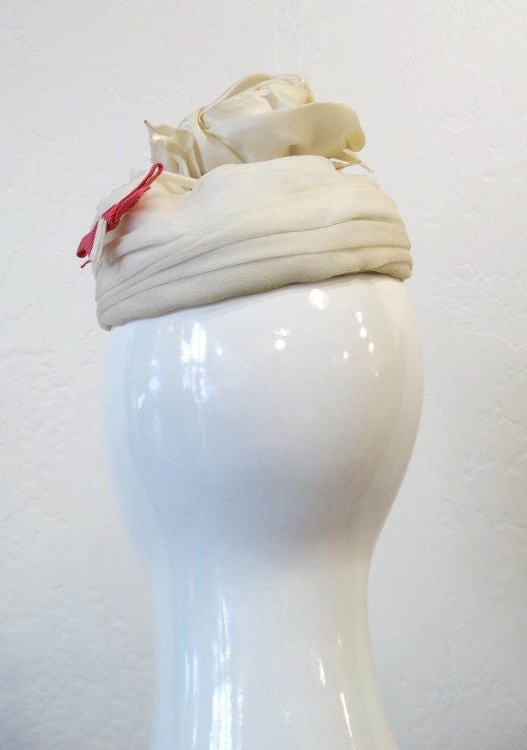 Feel Nothing But Chic In This Fascinator! Circa 1960s, this YSL fascinator features layered white sheer fabric and a white rose at the top. Includes white leafs and pink bows sticking out from under the base of the rose. Features removable
