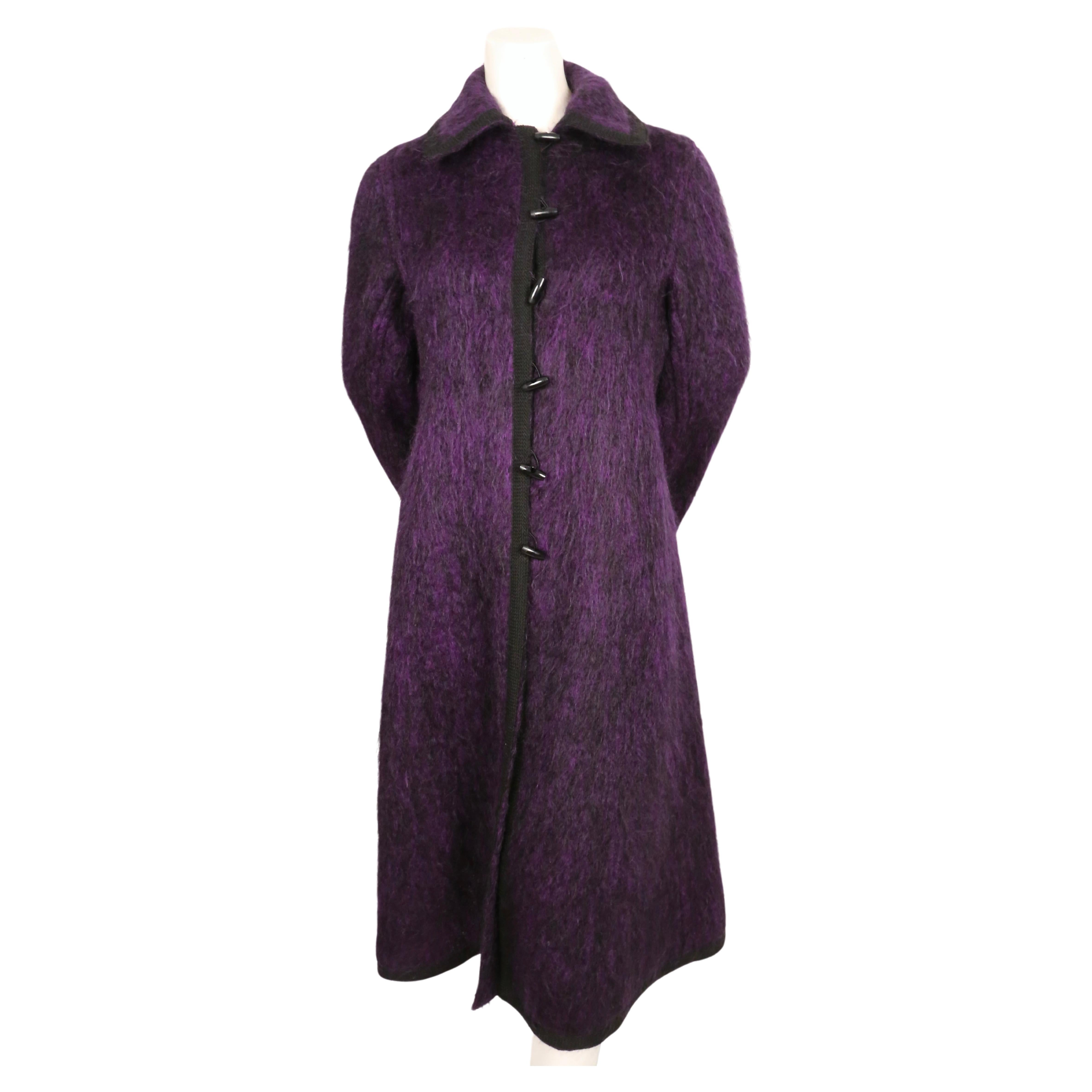 Dramatic, violet-purple, brushed-wool coat with black braided trim and toggle buttons from Yves Saint Laurent dating to the late 1960's. Coat has an A-line shape. Labeled a French size 40. Approximate measurements: inset shoulders 14.5
