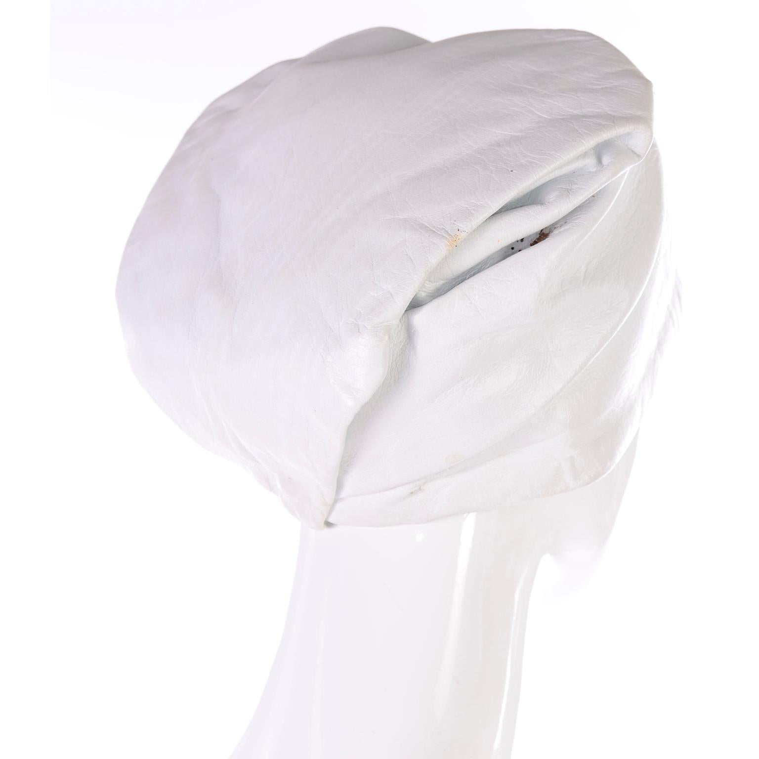 This is a very unique vintage YSL white leather hat with a fixed fold over envelope point in the back that creates a folded turban or bandana style look. This hat is really spectacular - the folds created by the folded point make it look loose and