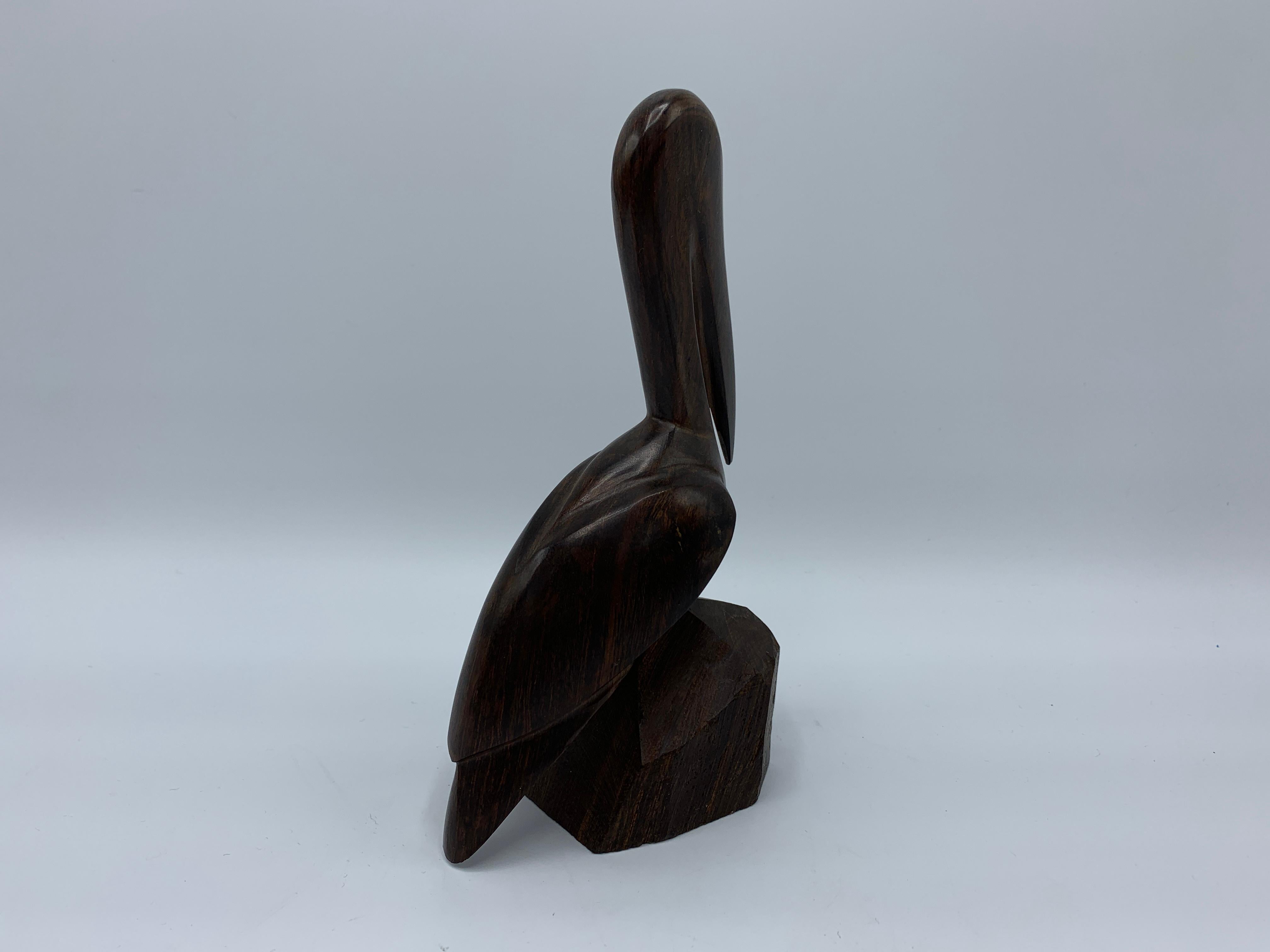 Offered is a gorgeous, hand carved, 1960s dark zebra-wood pelican sculpture. The piece has been left 'raw' along the rock shaped base that the sculpture is perched upon. We have a zebra wood road runner available as well.
