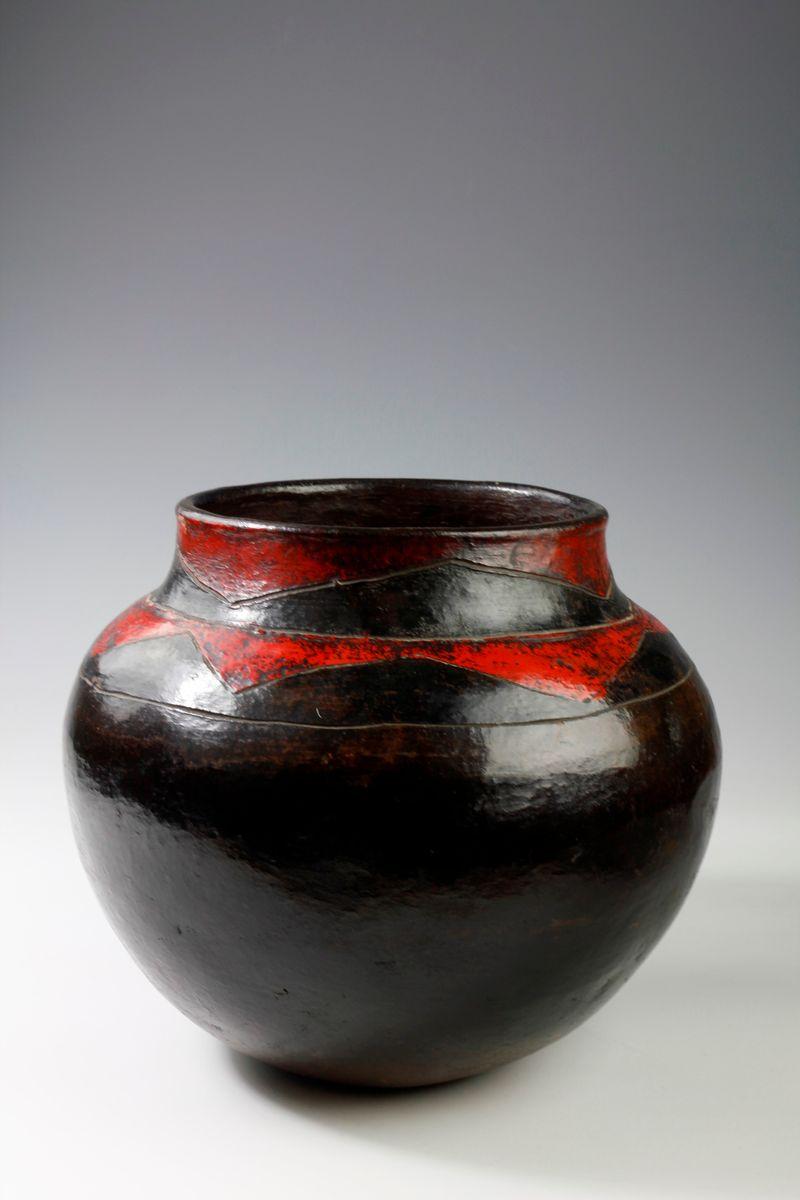 Made from fired earth, this 1960's Zulu storage pot has been attractively decorated with deep red house paint in chevron patterns around the rim. 
Formerly part of the London-based artist Romy Rey's collection, the pot is in good condition, and