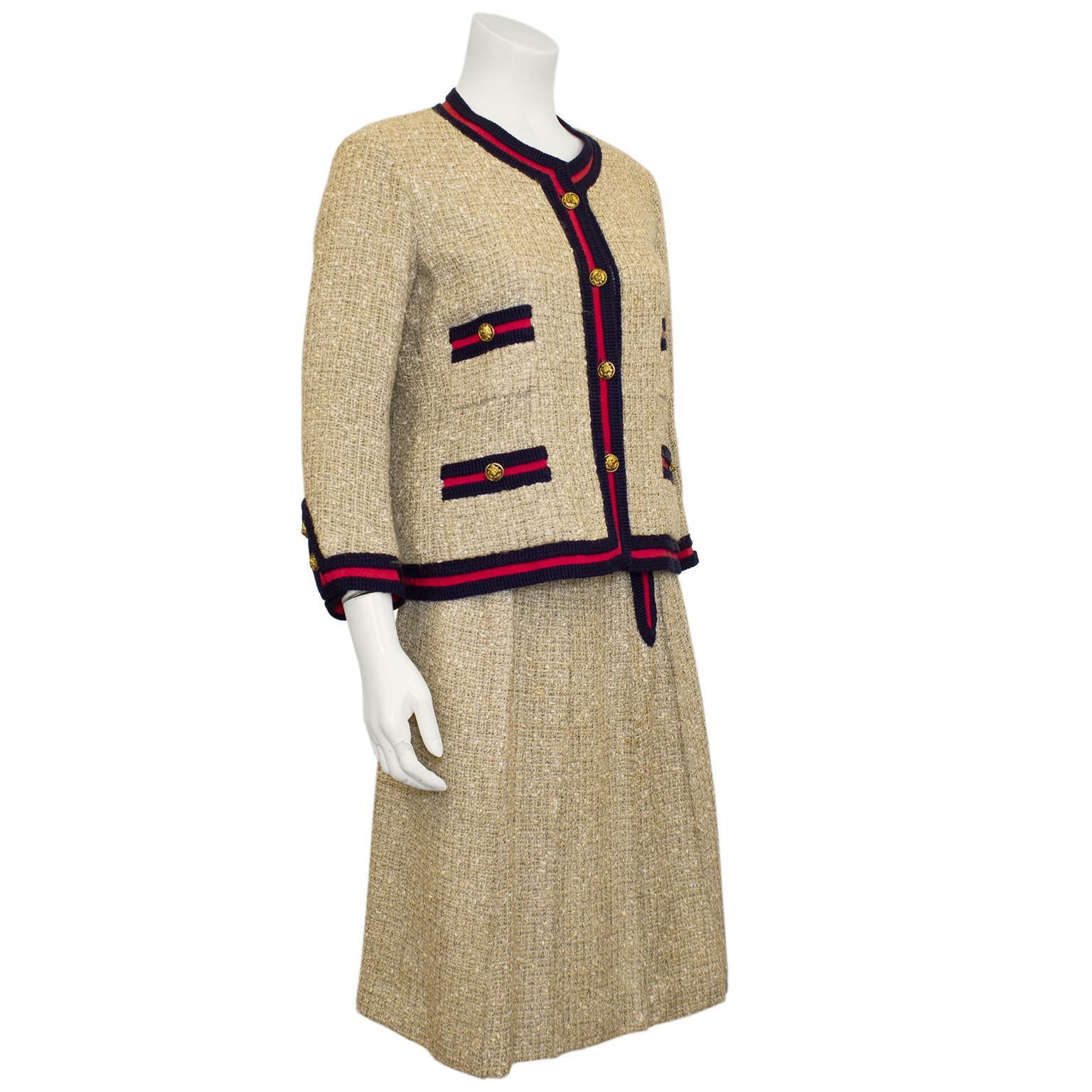 IT DOES NOT GET MORE ICONIC than this 1961 beige woven linen tweed skirt suit trimmed in raspberry red grosgrain ribbon and navy crochet border. This version was made exclusively for Holt Renfrew Canada. The same collection suit was worn by