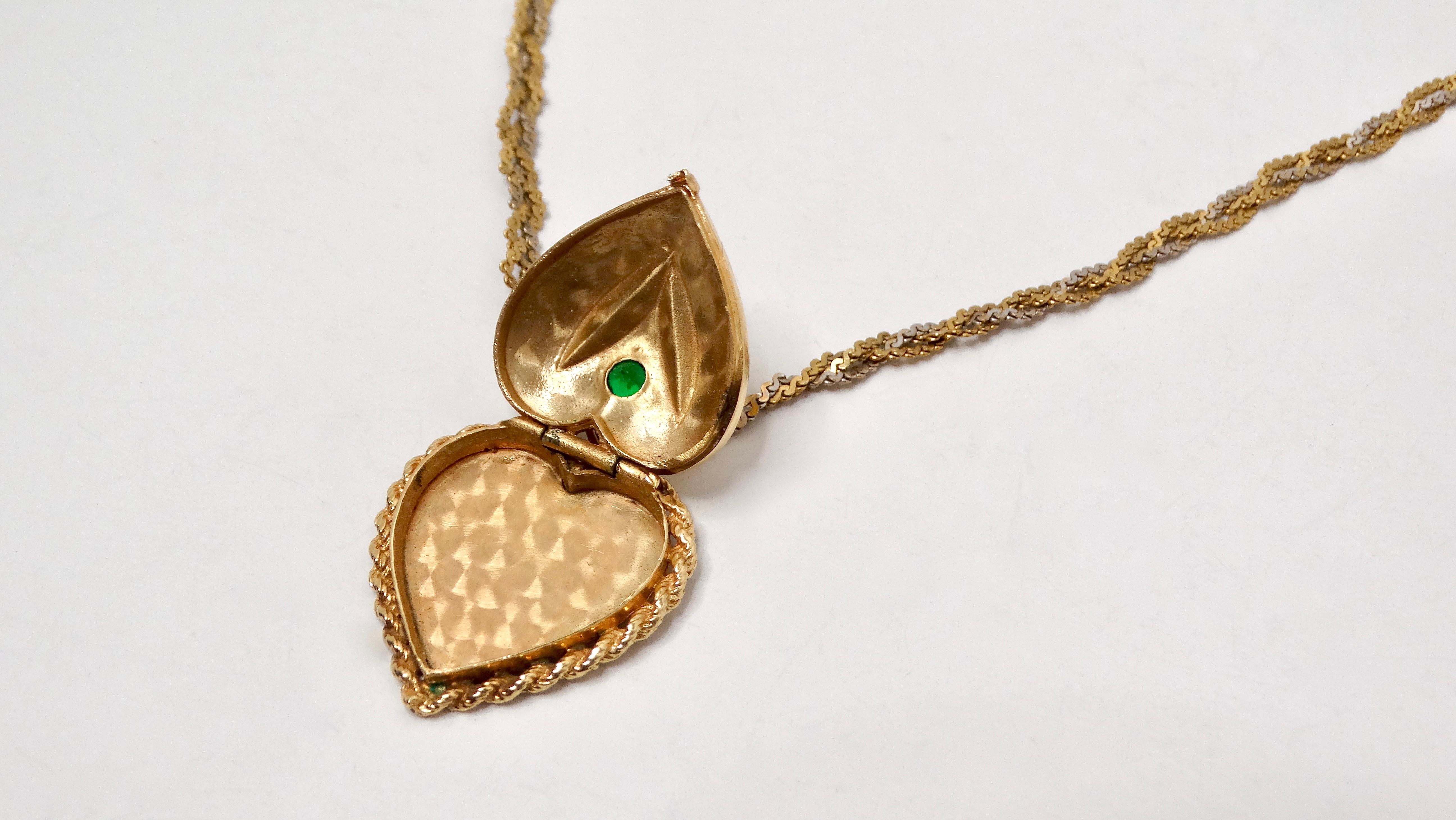 Torna all'eleganza del passato con questa raffinata collana con medaglione in oro 14k inciso a forma di cuore del 1961, ornato da un delicato motivo di fiori di smeraldo. Questo pezzo sentimentale è caratterizzato da un ciondolo a forma di cuore