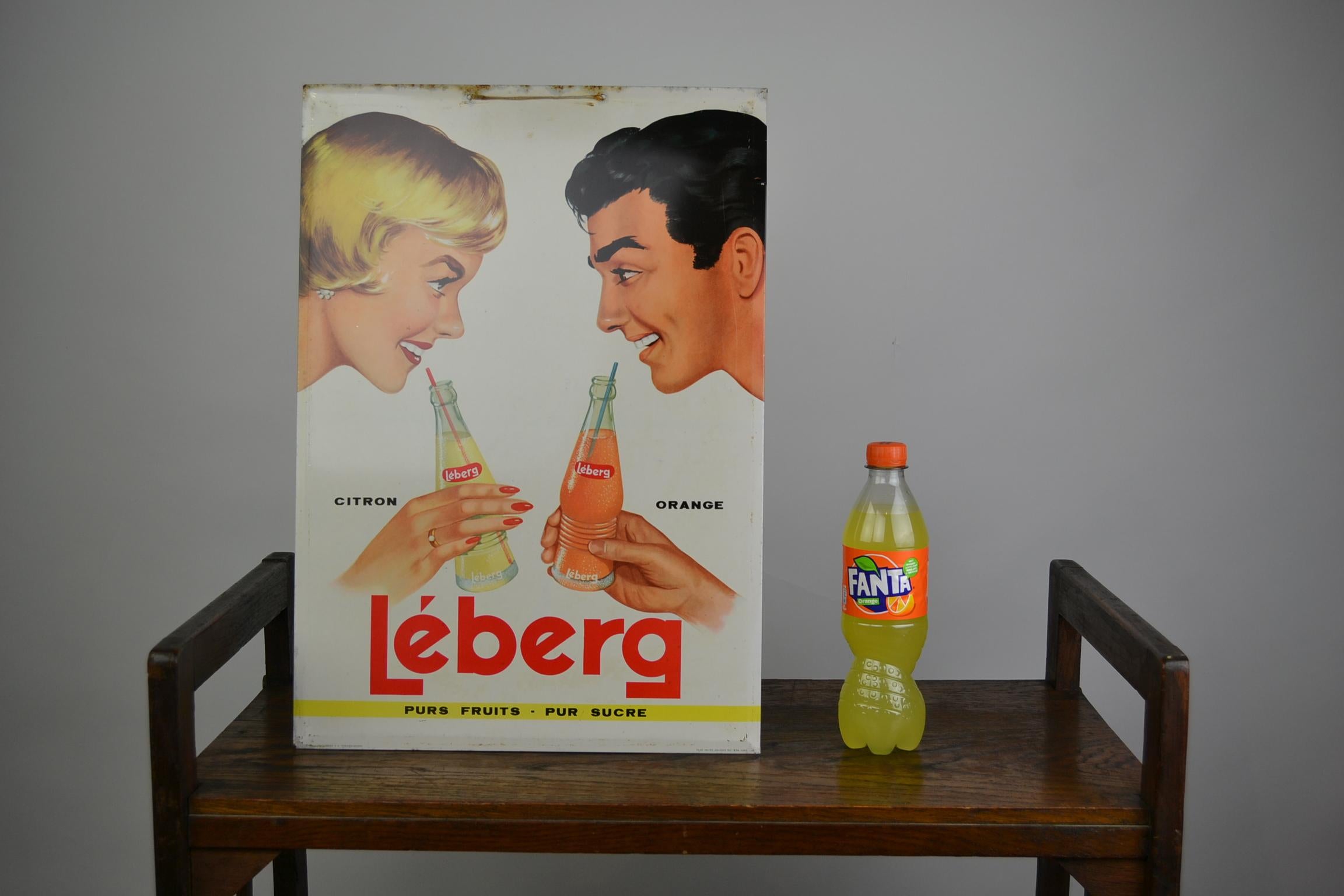 Romantic and cute metal advertising sign for Lemonade.
This old wall sign dates from 1961 and was made for the Company Leberg;
they started in 1933 with botteling water and lemonades.
A man and a woman are having a date and are drinking a lemon