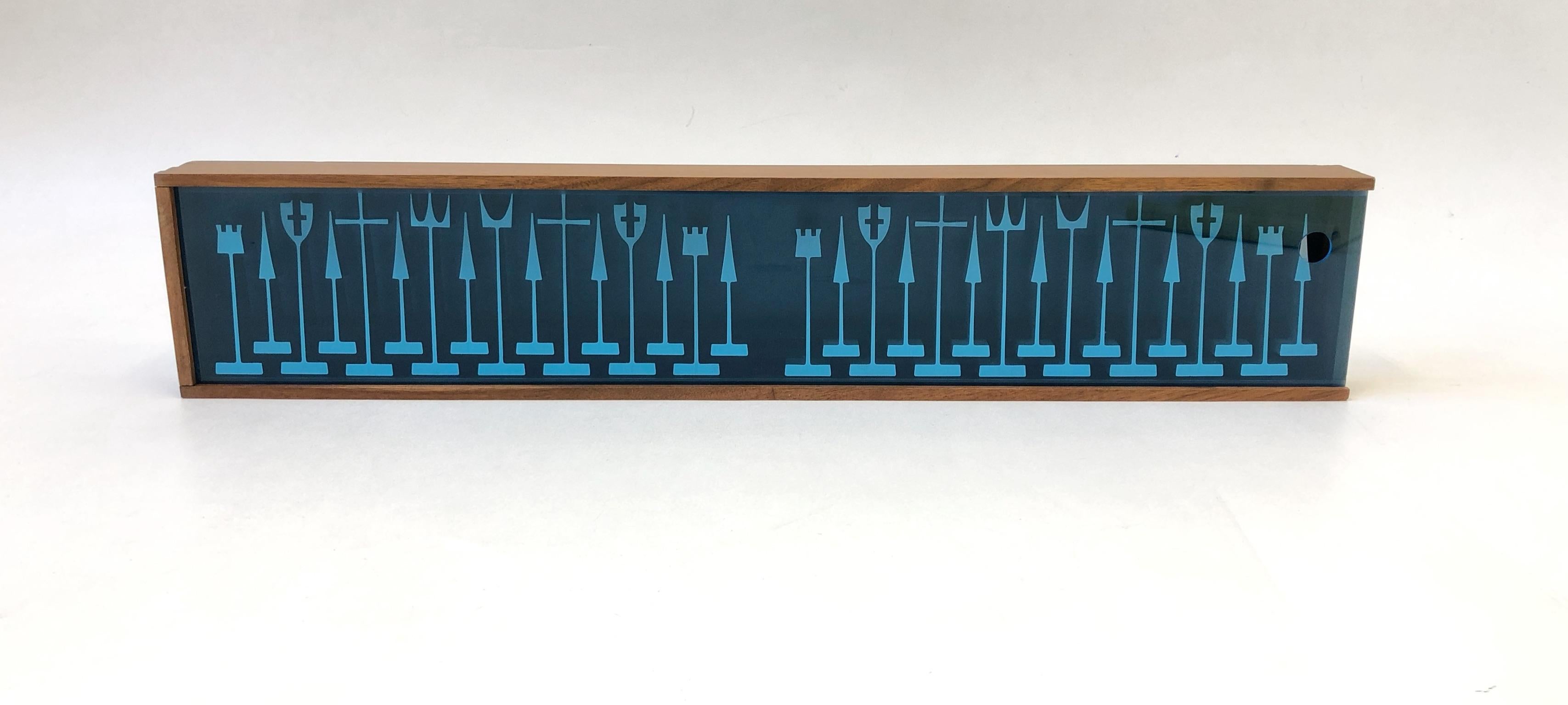 A spectacular aluminum chess set designed by Austin Cox for Austin Enterprises in 1962. The set is stored and displayed in a wall mountable walnut case with a blue acrylic cover. All of the pieces are marked (1962 Austin Enterprises).

Dim: 
The