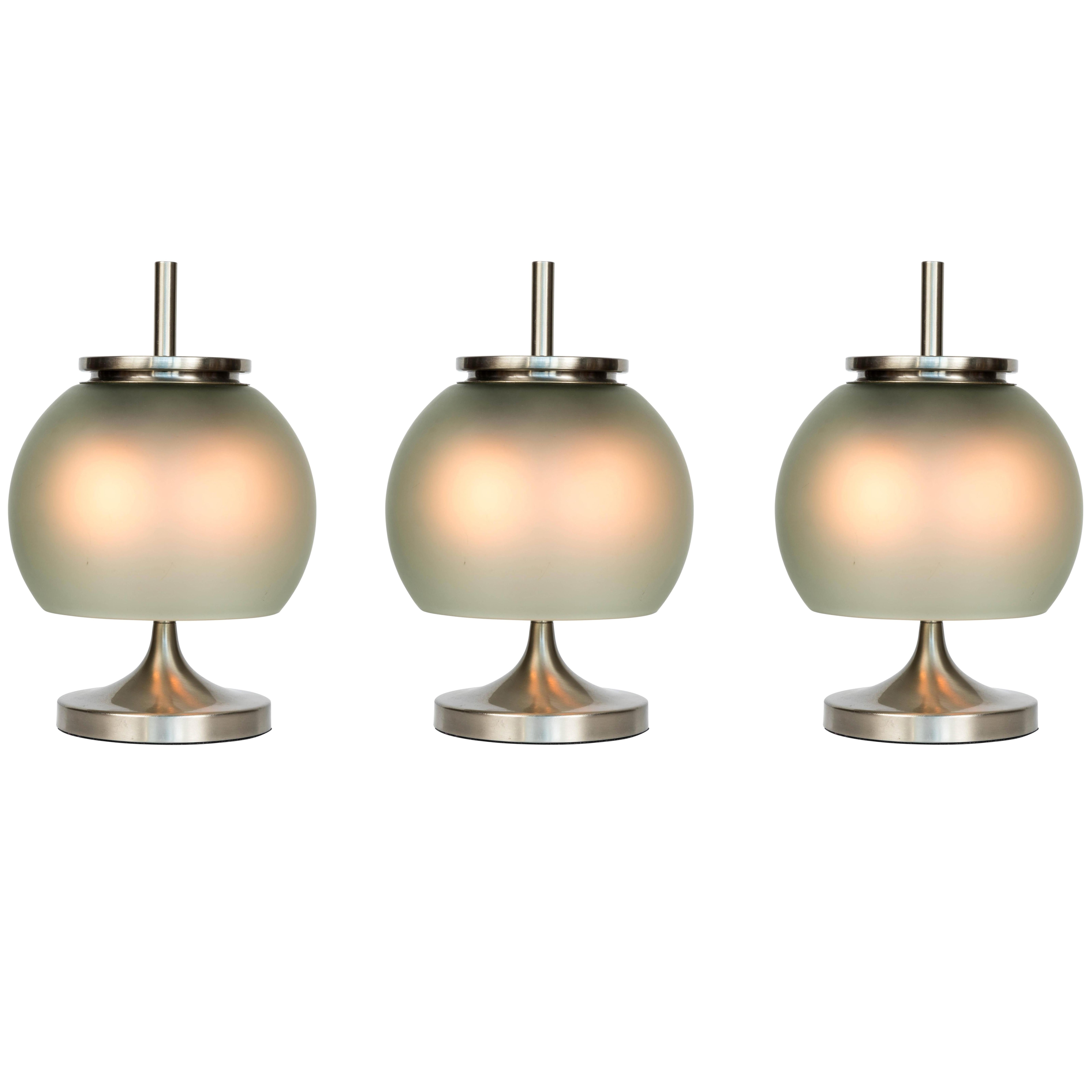 1962 Emma Gismondi Schweinberger 'Chi' Table Lamps for Artemide. This uniquely elegant table lamp is produced in nickeled brass and hand blown green opaline glass. An highly refined and iconic midcentury design that is quintessentially Italian. Two