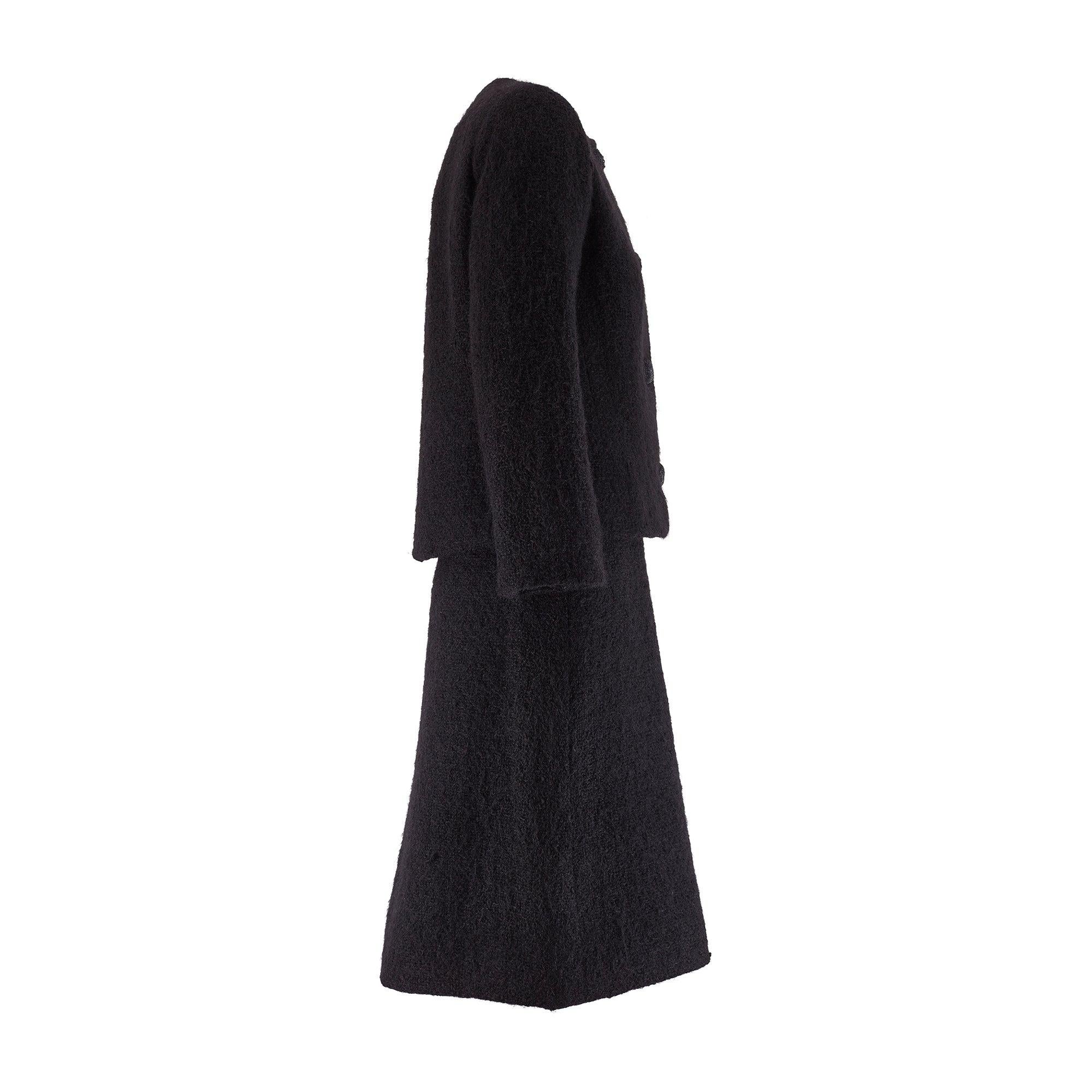 This documented Autumn / Winter 1962-1963 Hubert de Givenchy haute couture two-piece skirt suit is crafted from a luxurious black angora wool which has a highly textured, fluffy feel. The jacket is collarless. It is tailored to a boxy silhouette