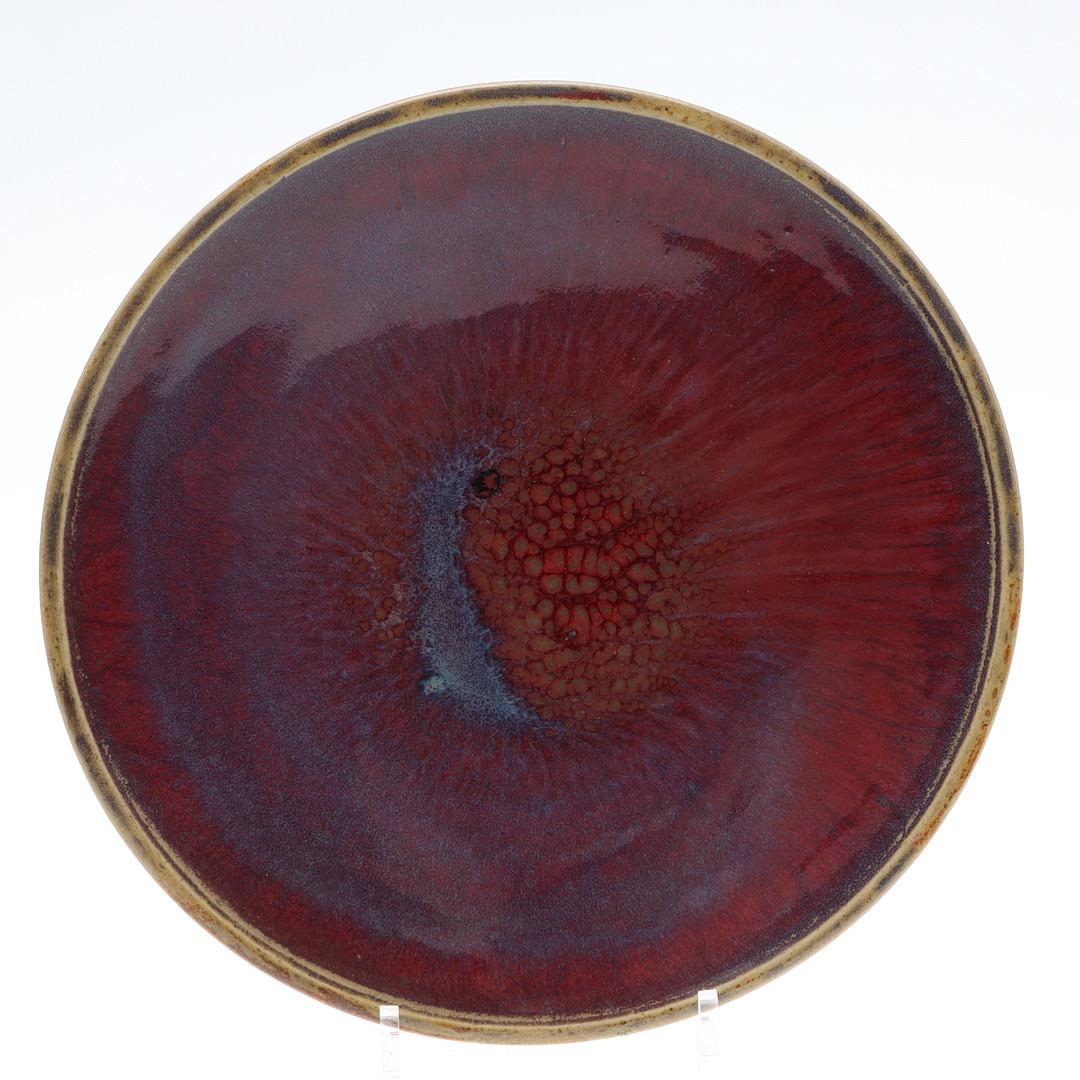 Plato decorativo de gres esmaltado con la famosa técnica ''Sangre de Buey'', desarrollada por ceramistas suecos a mediados del siglo XX. Con tonos rojo intenso - burdeos con matices morados, azules y tierra. 

Henning Nilsson
Suecia (1907-