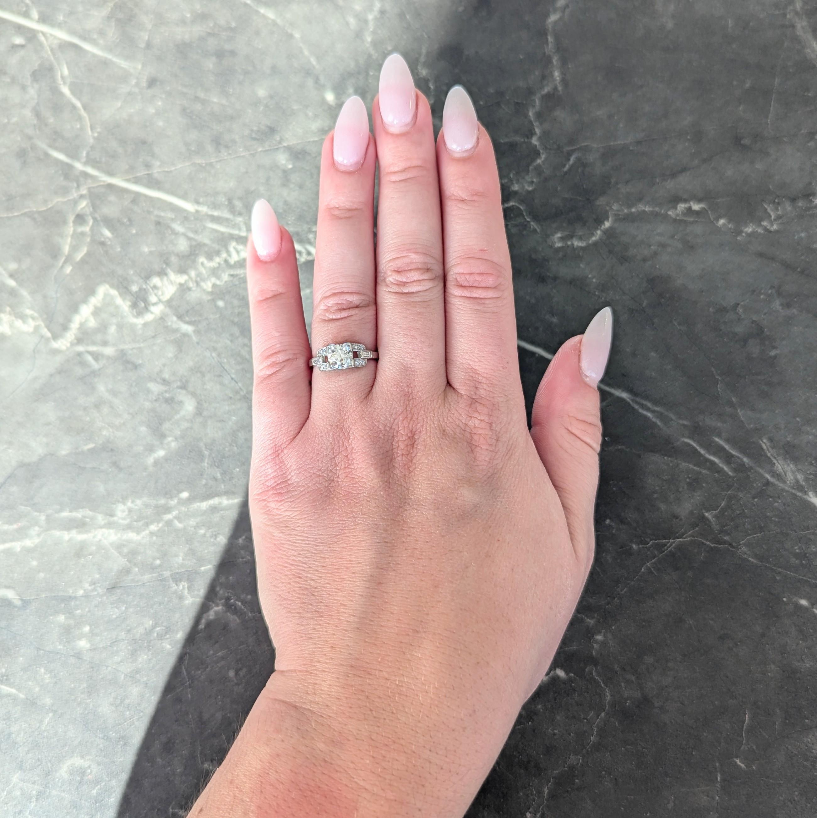 Centering a transitional cut diamond weighing approximately 0.87 carat - I color with VS clarity
Bead set in a square form head and flanked by pierced buckle motif shoulders
Bead and flush set throughout with single and baguette cut