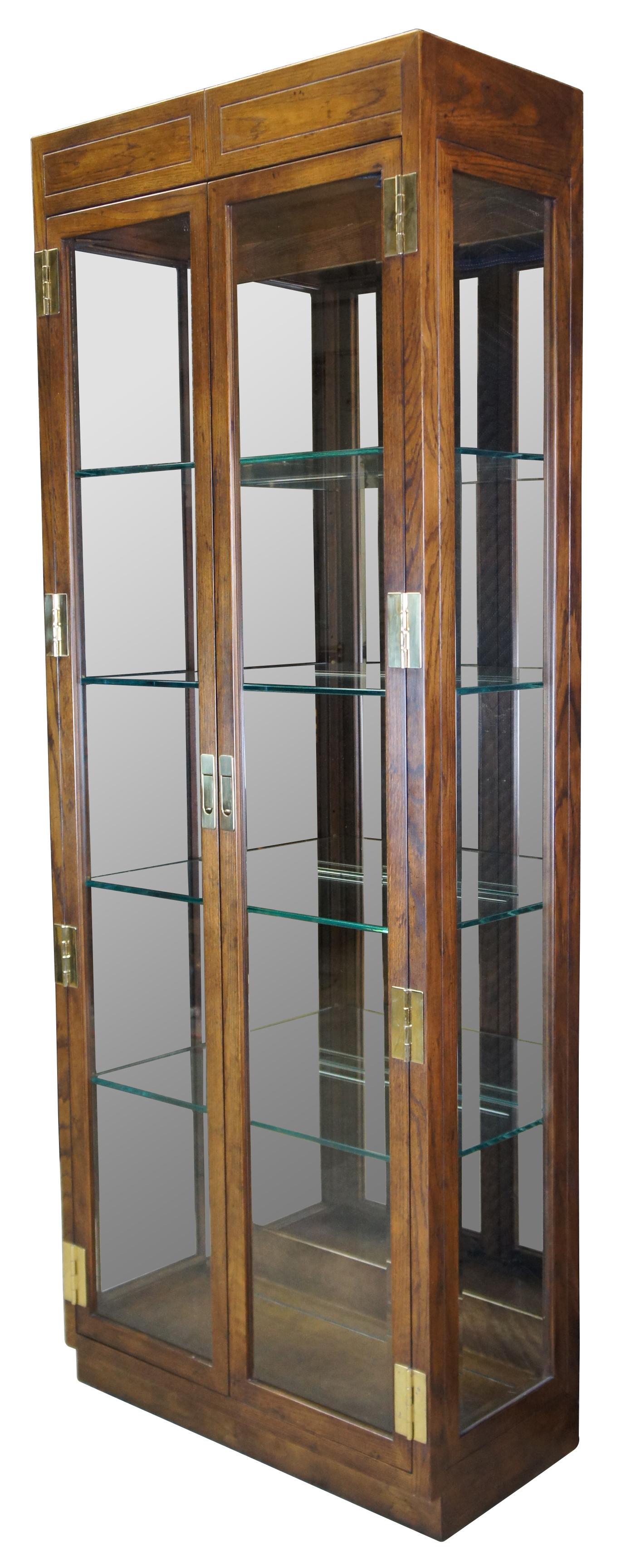 Mid-century Henredon Scene one display illuminated cabinet or vitrine. Made of oak featuring campaign styling with beveled glass sides / doors, brass hardware, and adjustable shelving with plate grooves.
9105-49. 160267. Circa 1964.