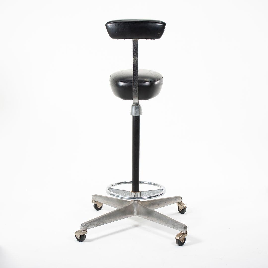 This is a ‚ÄúPerch‚Äù office stool, designed by George Nelson & Robert Propst for Herman Miller in 1964. The design was part of Nelson‚Äôs Action Office system. The stool consists of a padded black naugahyde seat and one arm, which can serve as both