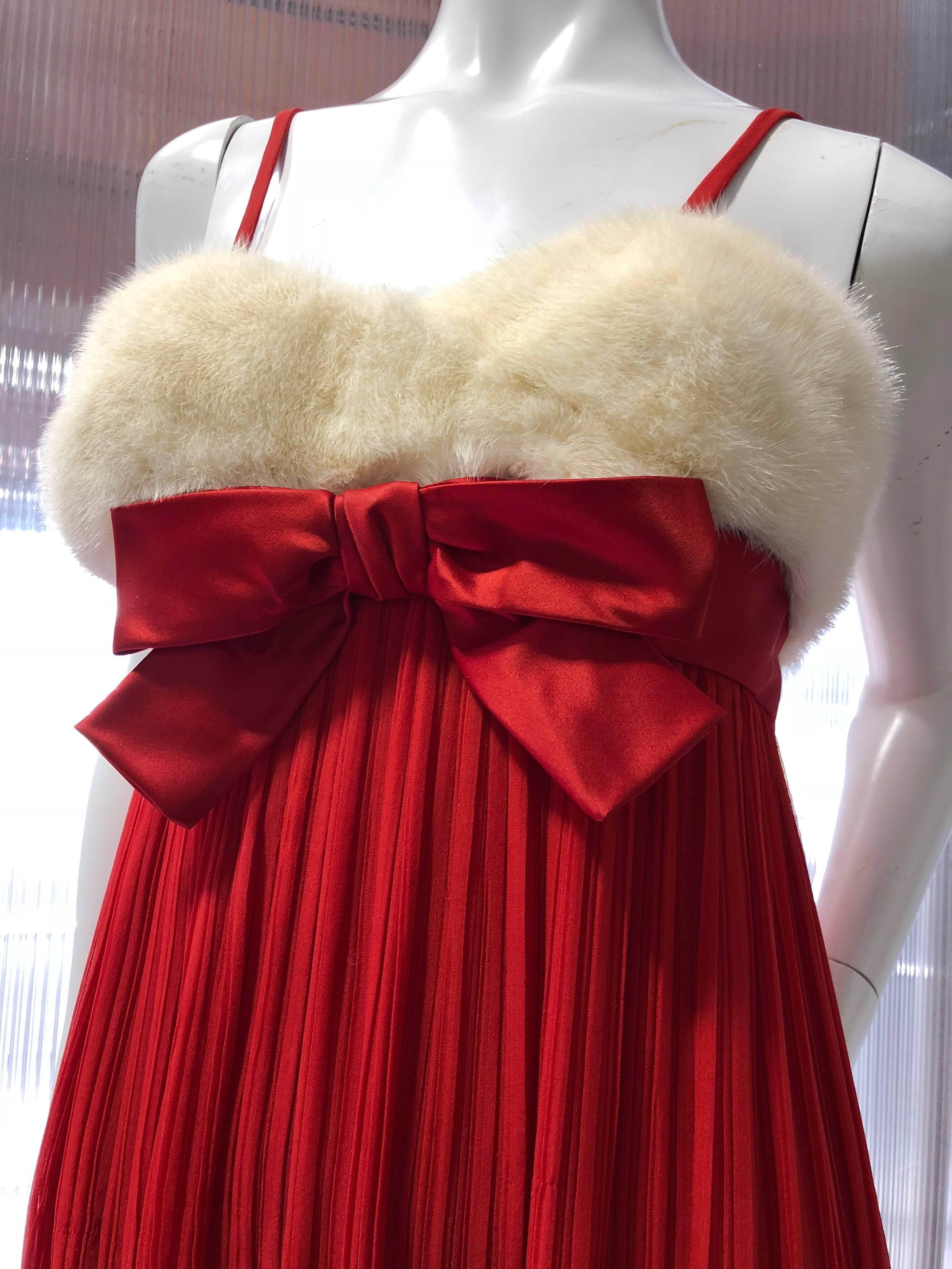 1964 Sarmi roter Seidenchiffon im Fortuny-Stil, plissiertes Abendkleid mit Empire-Taille, konstruiertem und entbeintem Mieder, verziert mit einer roten Satinschleife und weißem Nerzfell. Rückseite mit Reißverschluss und Haken.  Vollständig
