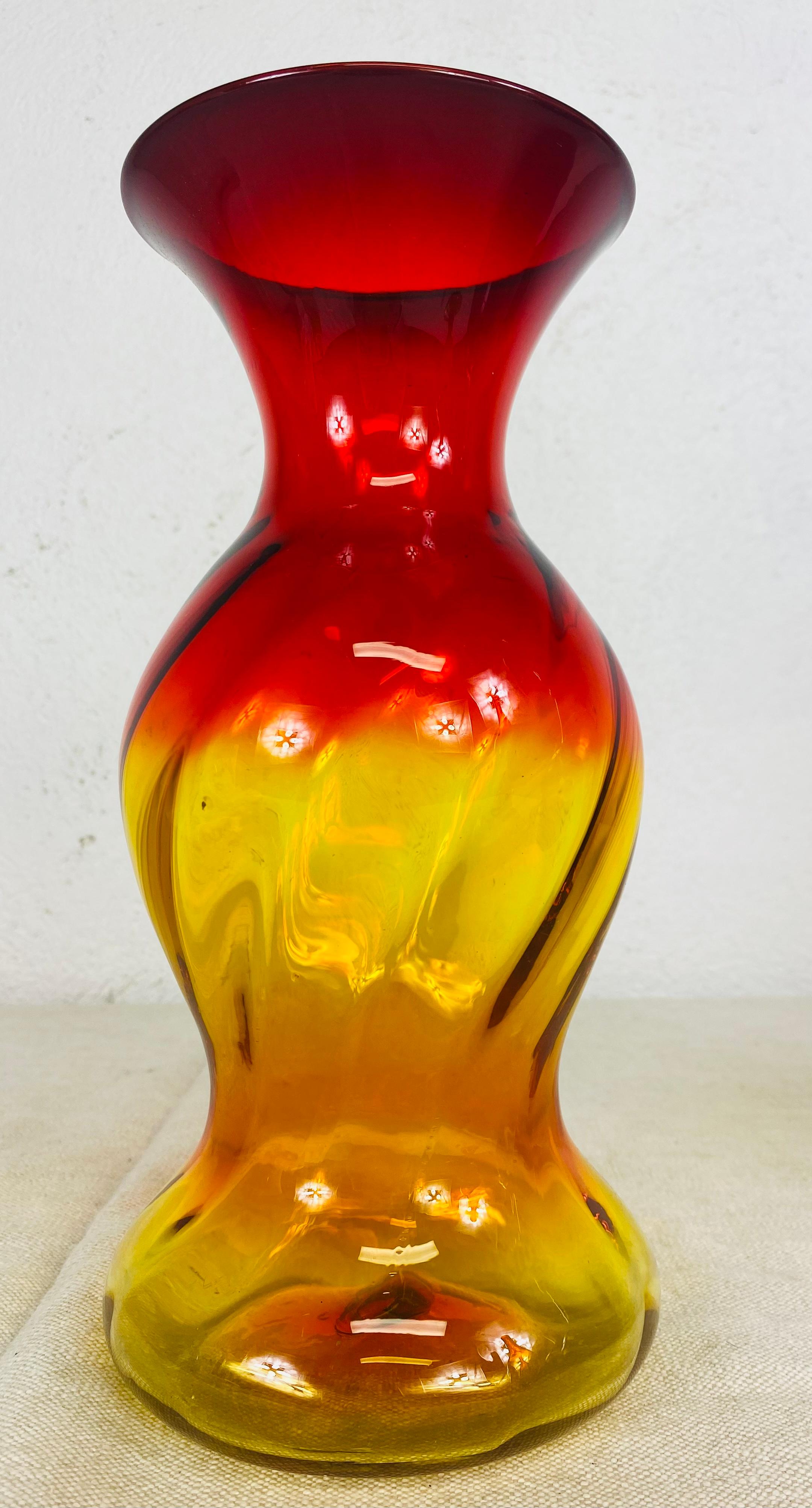 Si tratta di un vetro soffiato a mano originale Blenko con identificazione del pontile sottostante, del 1965 circa, di Wayne Husted; ambarina con riflessi arancioni. Gli altri oggetti in vetro mostrati sono solo per esposizione e possono essere