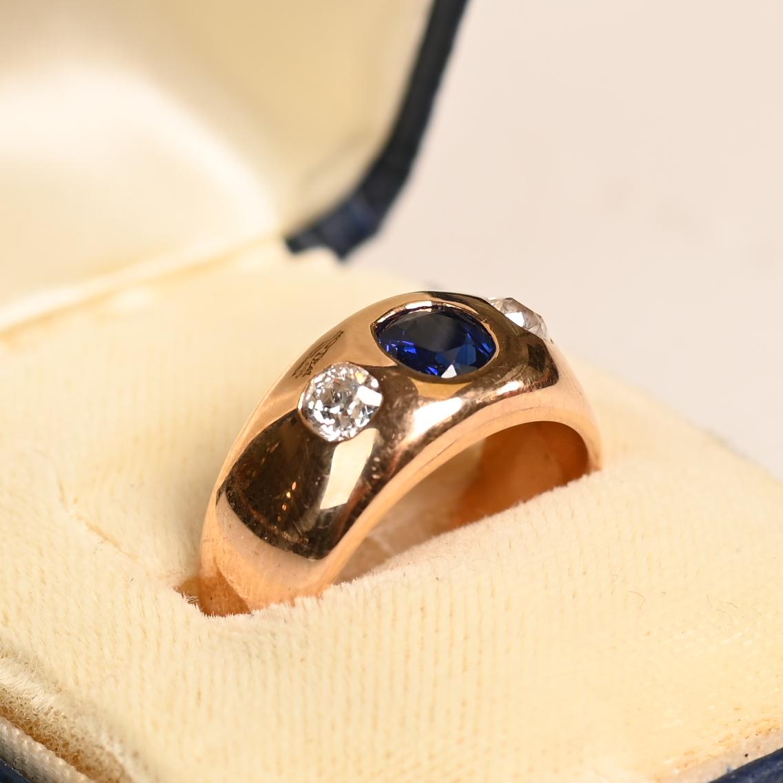 Anello francese vintage con tre pietre, elegantemente realizzato a mano in oro giallo 18 carati nel 1965 circa. Al centro, un affascinante zaffiro naturale a taglio rotondo, del peso di circa 0,50 carati, irradia tonalità profonde e ricche. Lo