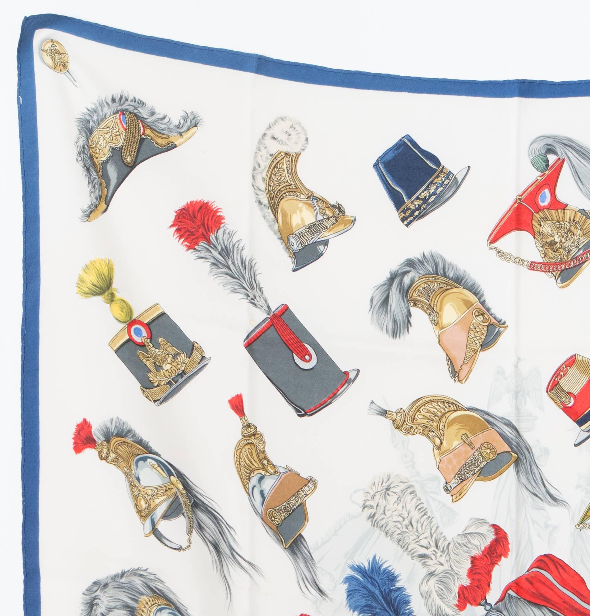 Écharpe en soie ivoire 1956 Hermès Casques et Coiffures Militaires par Françoise Heron:: avec des coiffures militaires:: un contour bleu et une signature Hermès. 
Circa : 1956
35::4in. (90cm) X 35::4in. (90cm)
 En excellent état vintage. Fabriqué en