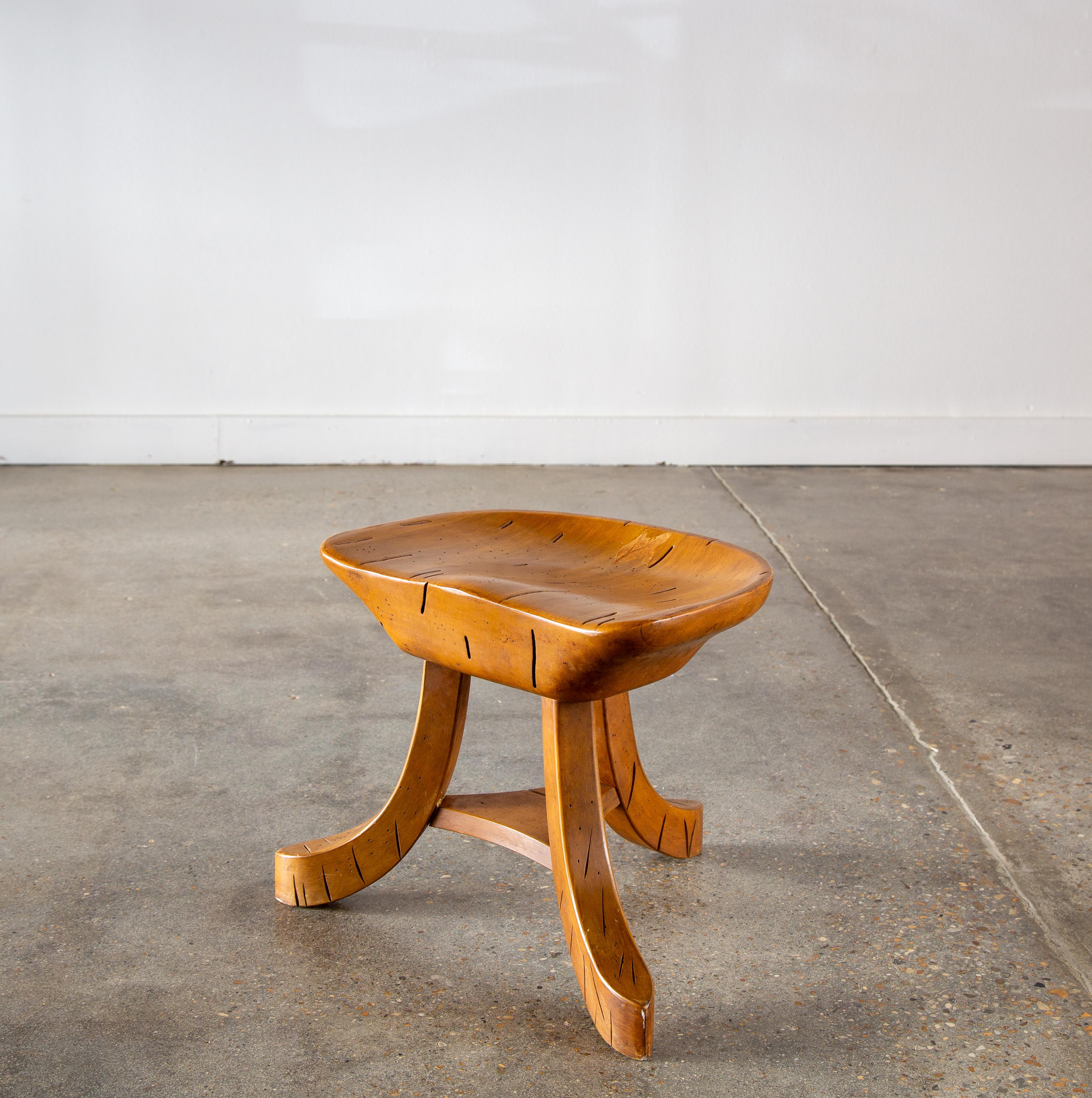 Solid ambrosia maple featuring beetle and worm holes and tunnels throughout.  This stool with a thick hand carved seat elevated by three splayed legs features a brass plaque on the bottom which reads Madison Avenue Milking stool XMAS 1966. Similar