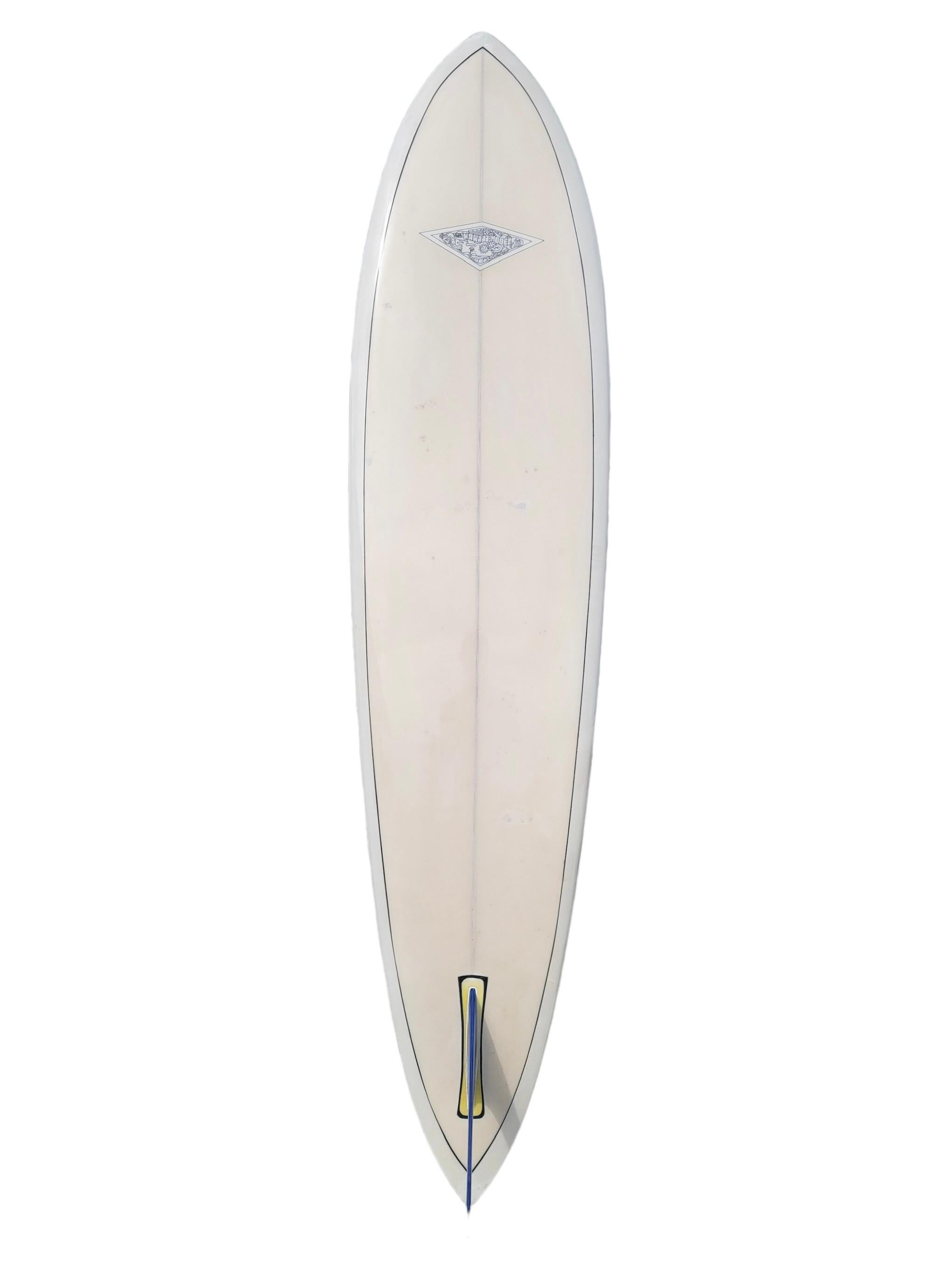 Tabla de surf vintage 1967 modelo Hobie Hawaii. Presenta un diseño en forma de cola de alfiler con pigmento blanco y rayas azules brillantes. Logotipo del modelo Hobie Hawaii de muy baja producción. Como se ve en el libro de tapa dura 